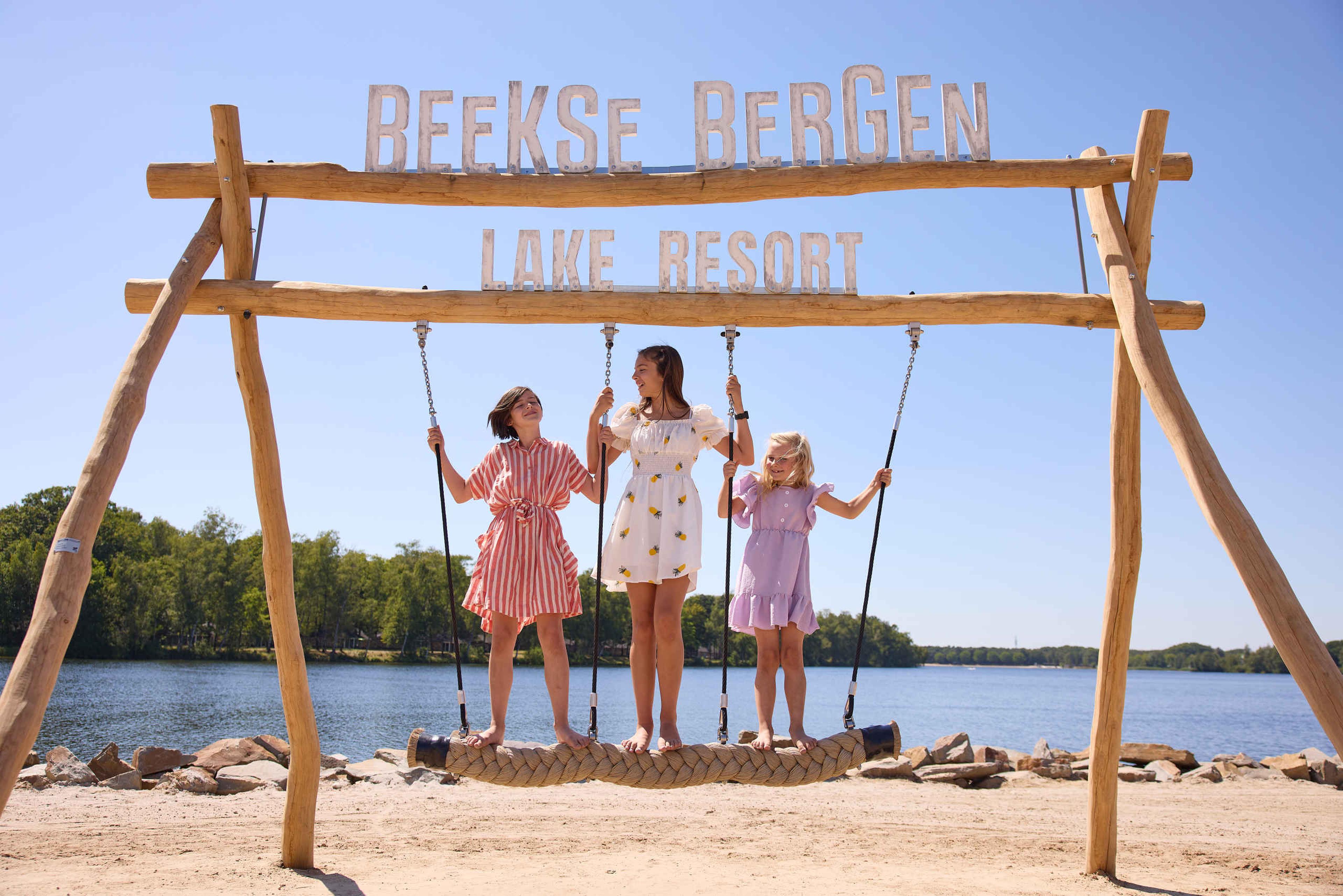 Kinderen op een schommel op het speelstrand bij het Victoriameer bij Lake Resort Beekse Bergen