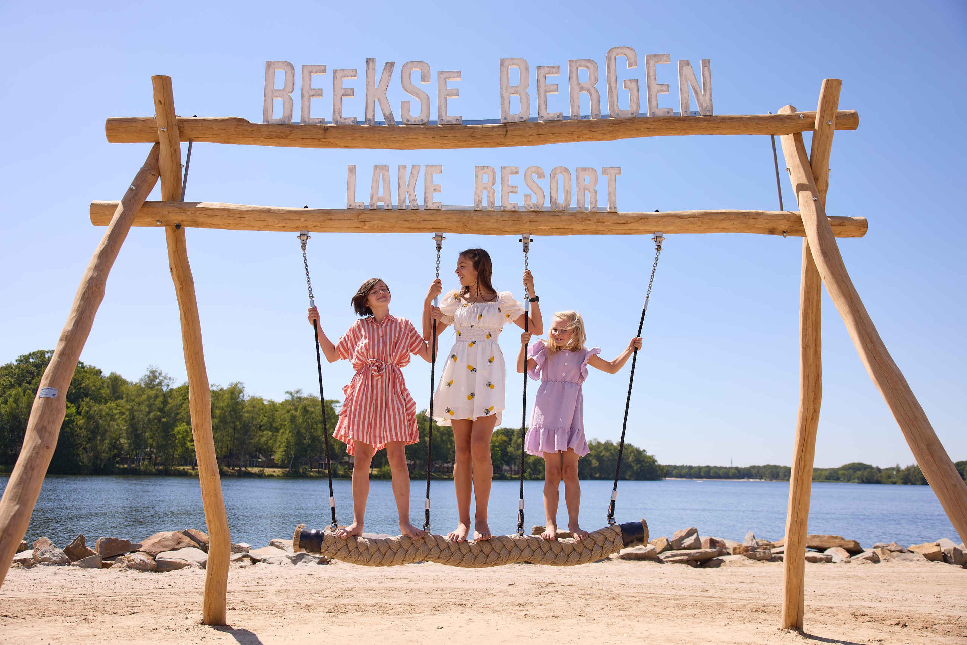 Kinderen op een schommel op het speelstrand bij het Victoriameer bij Lake Resort Beekse Bergen