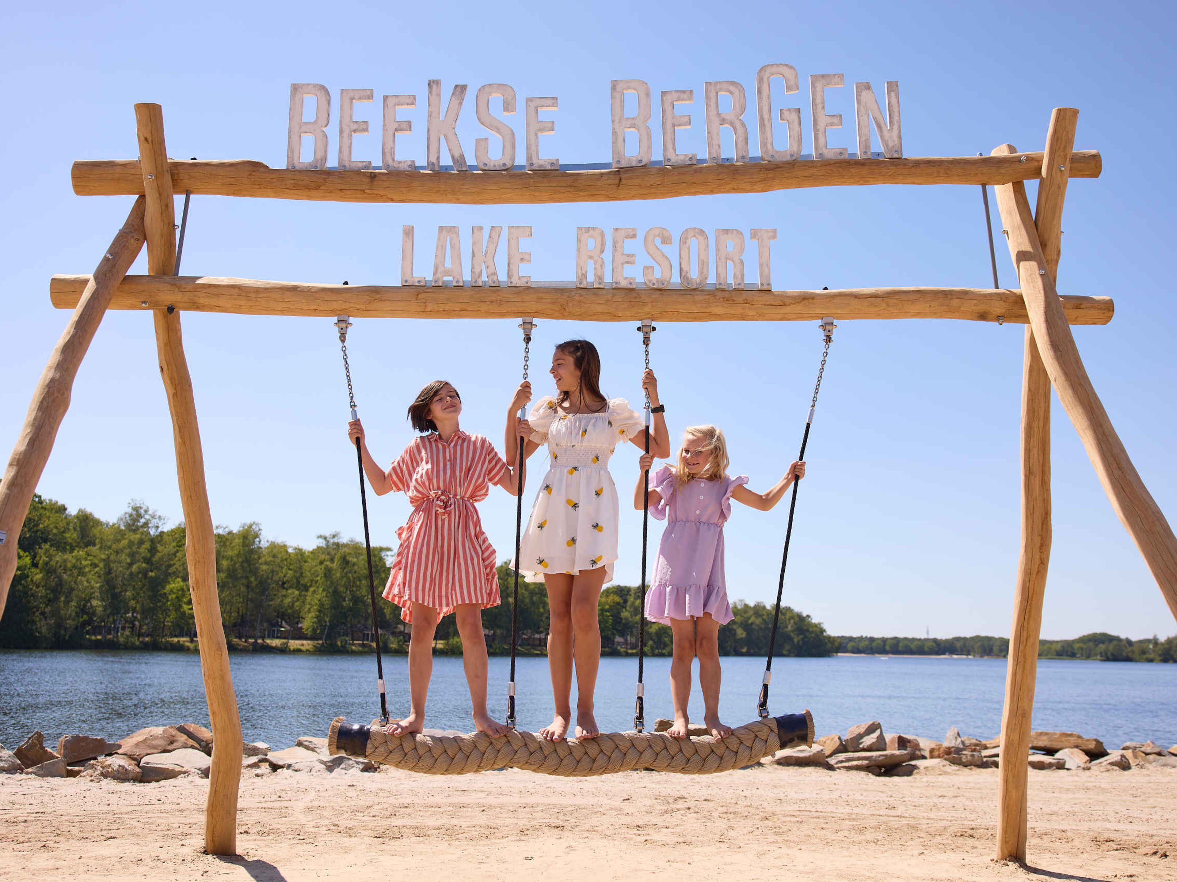 Kinderen op een schommel op het speelstrand bij het Victoriameer bij Lake Resort Beekse Bergen