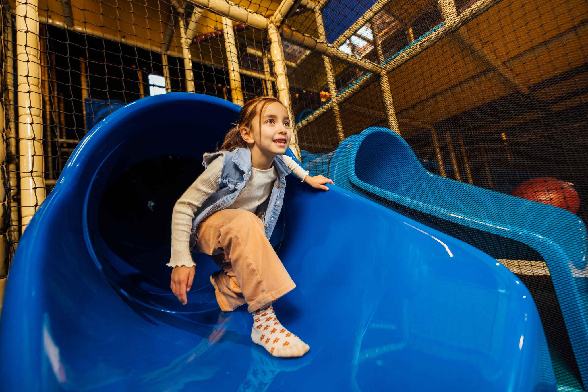 Een meisje klimt uit de glijbaan van Speelland Indoor bij Beekse Bergen