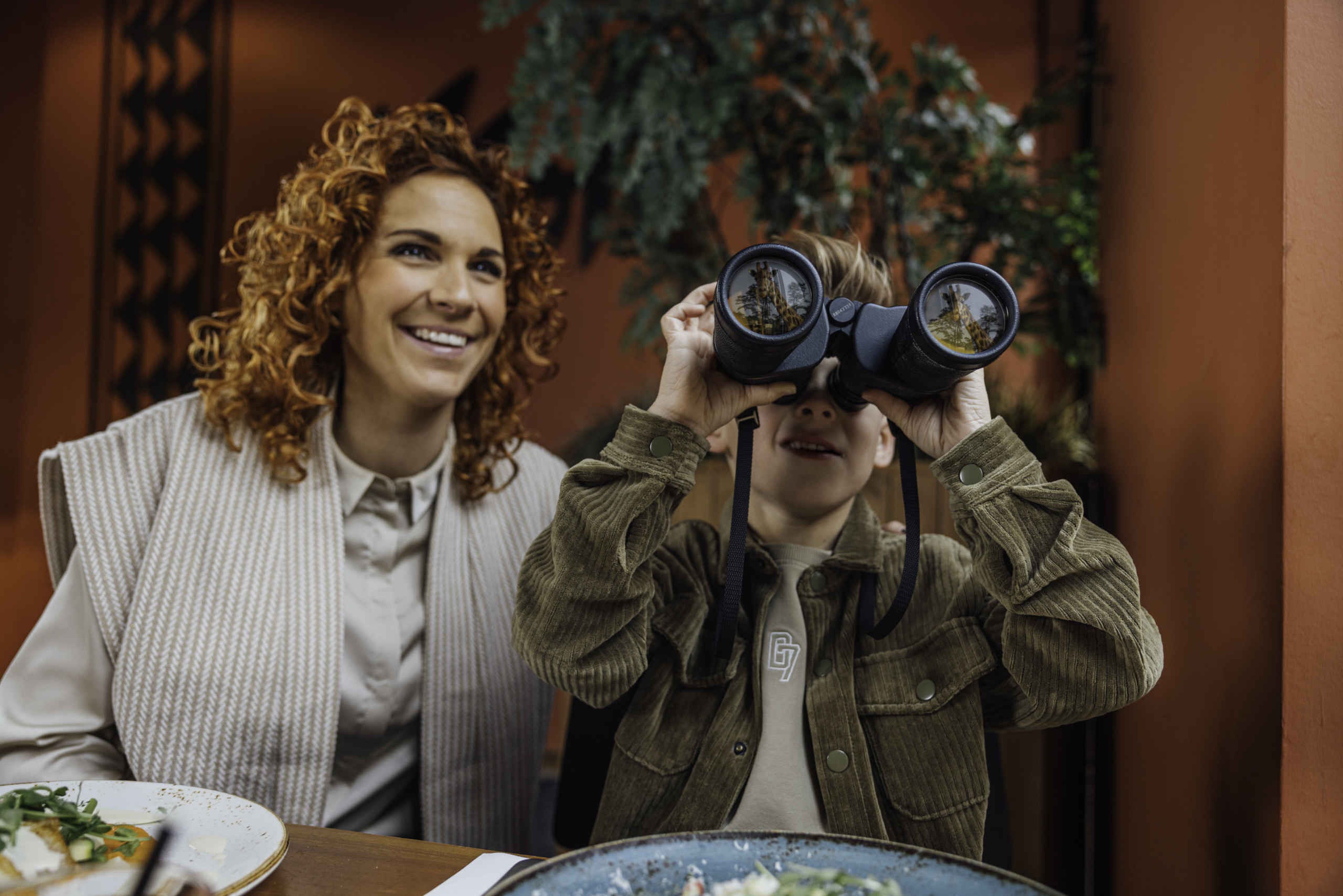 Een vrouw en haar zoon kijken naar de savanne bij restaurant Moto in Safari Resort Beekse Bergen