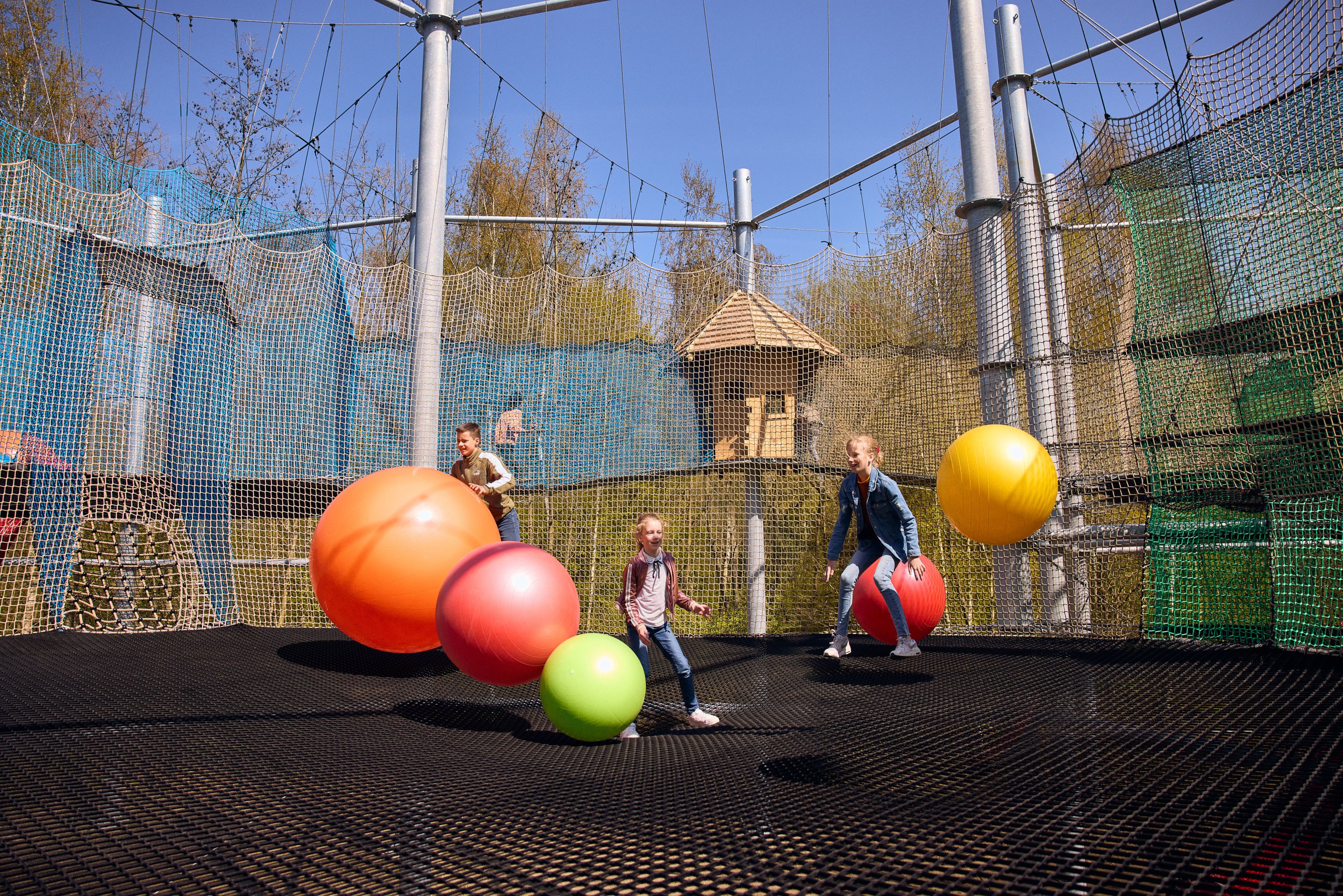 Kinderen springen met ballen in het Netten Adventure van Klimrijk Brabant