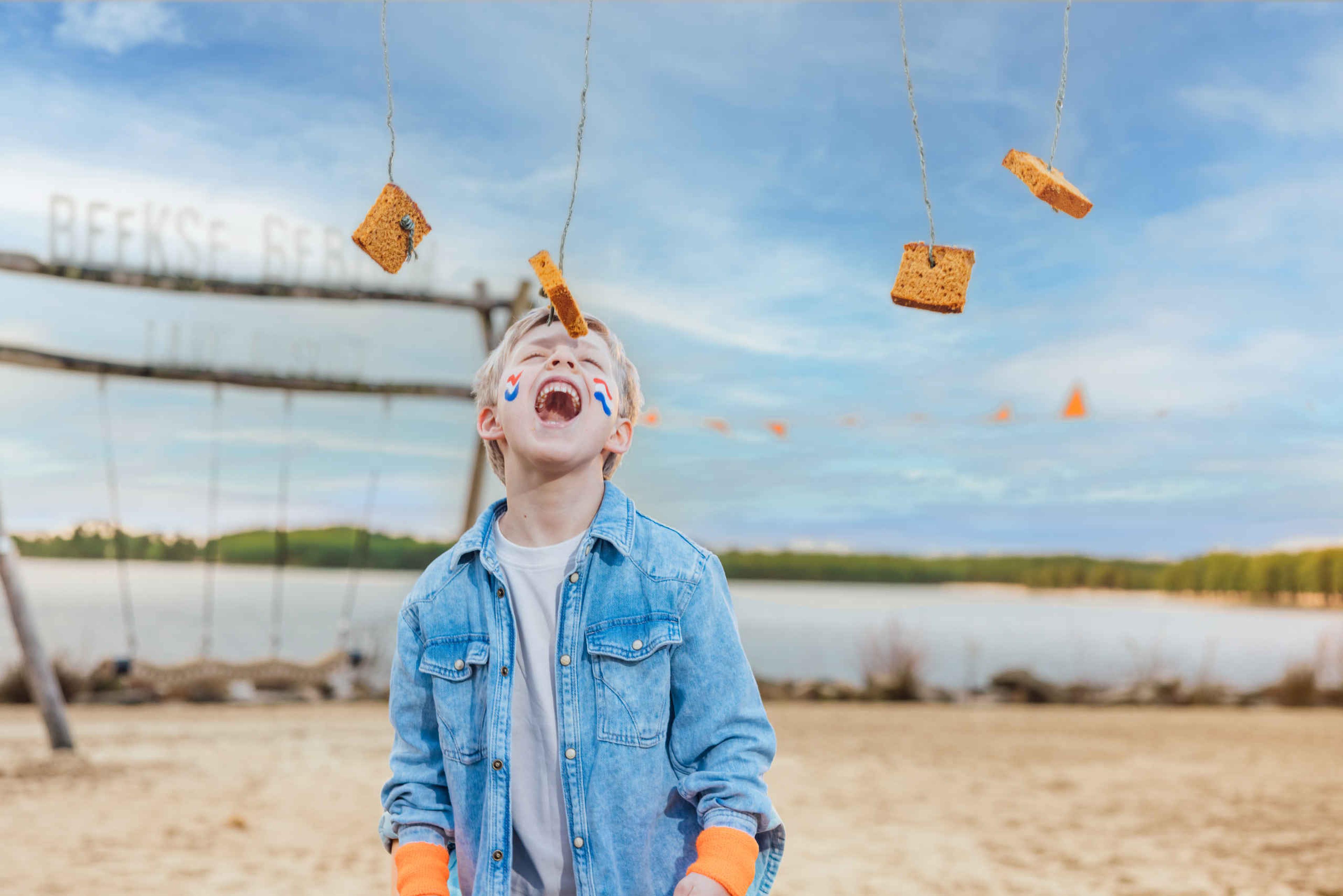 Een jongen is aan het koekhappen tijdens de koningsspelen bij Lake Resort Beekse Bergen.