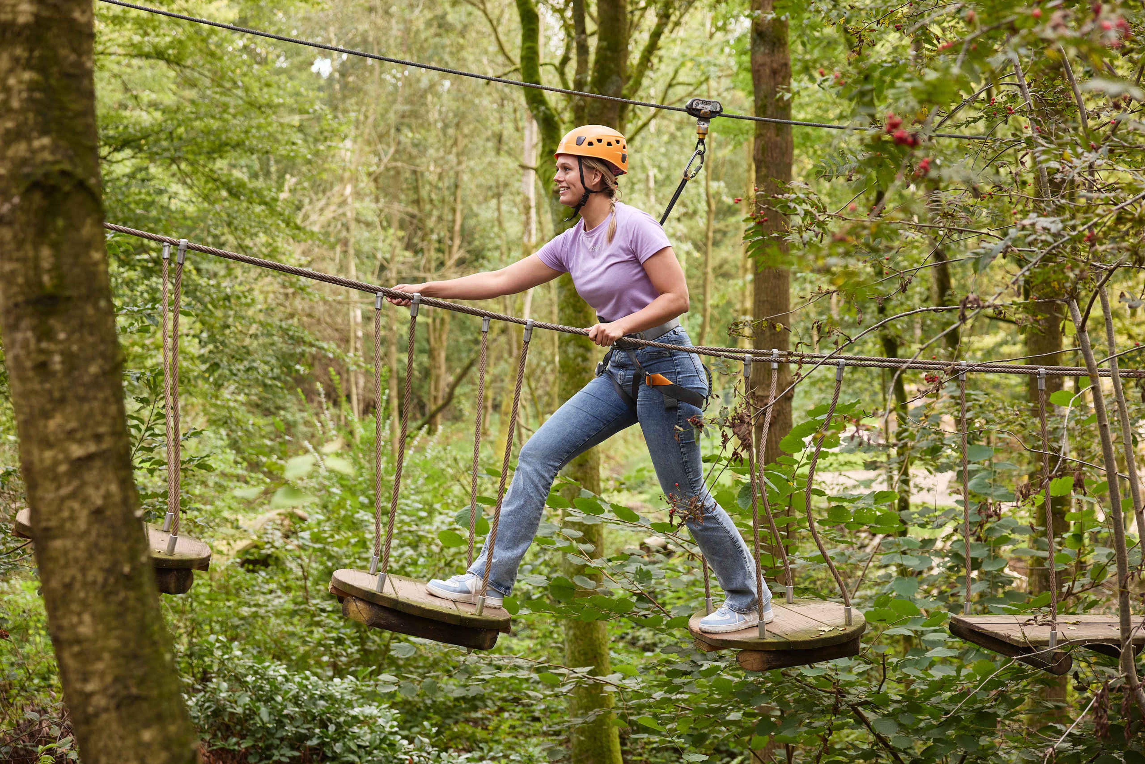 Een vrouw op de platform brug van route 3 van het Klimparcours bij Klimrijk Brabant