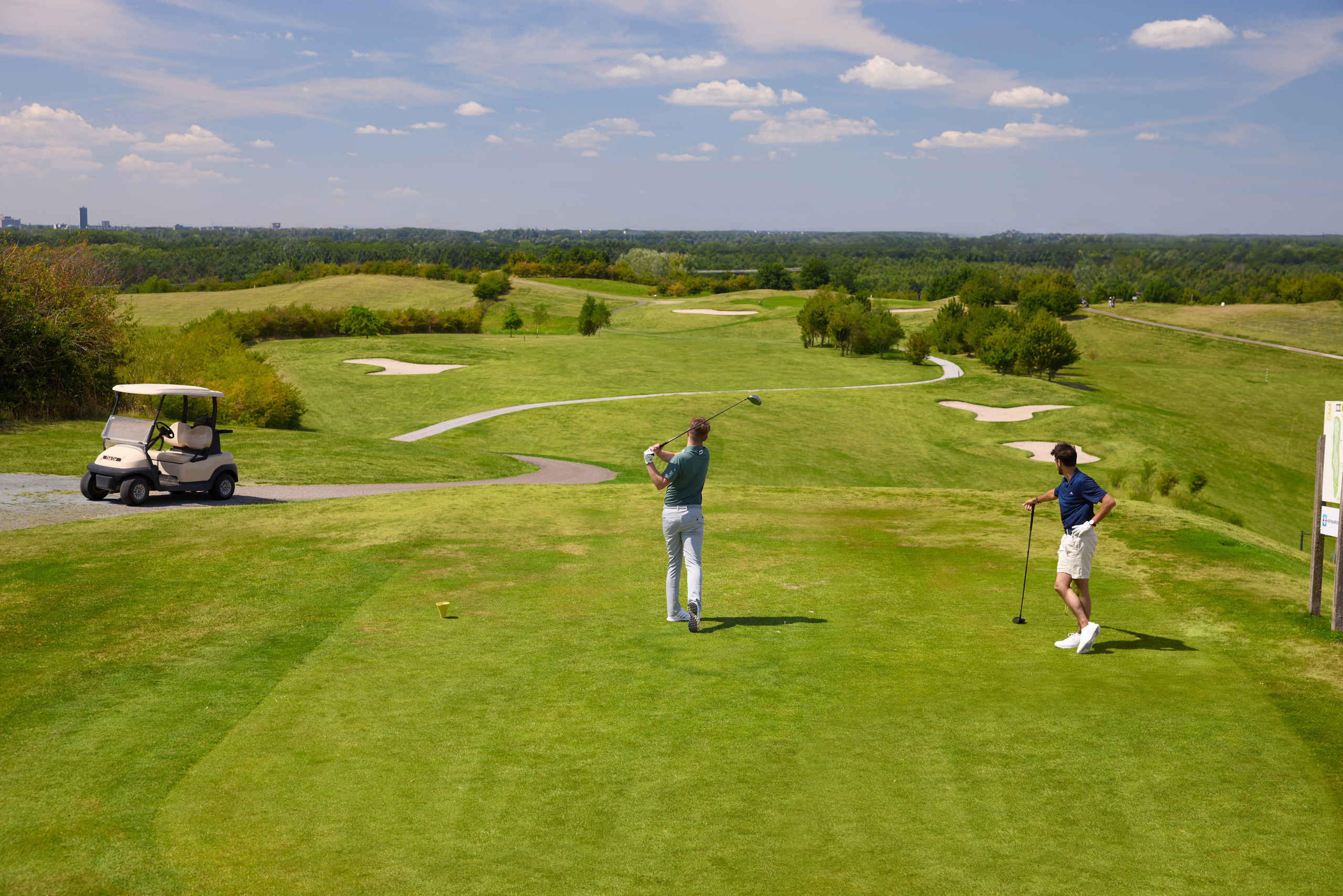 Twee mannen slaan af op de teebox van hole 3 van Golf De Gulbergen