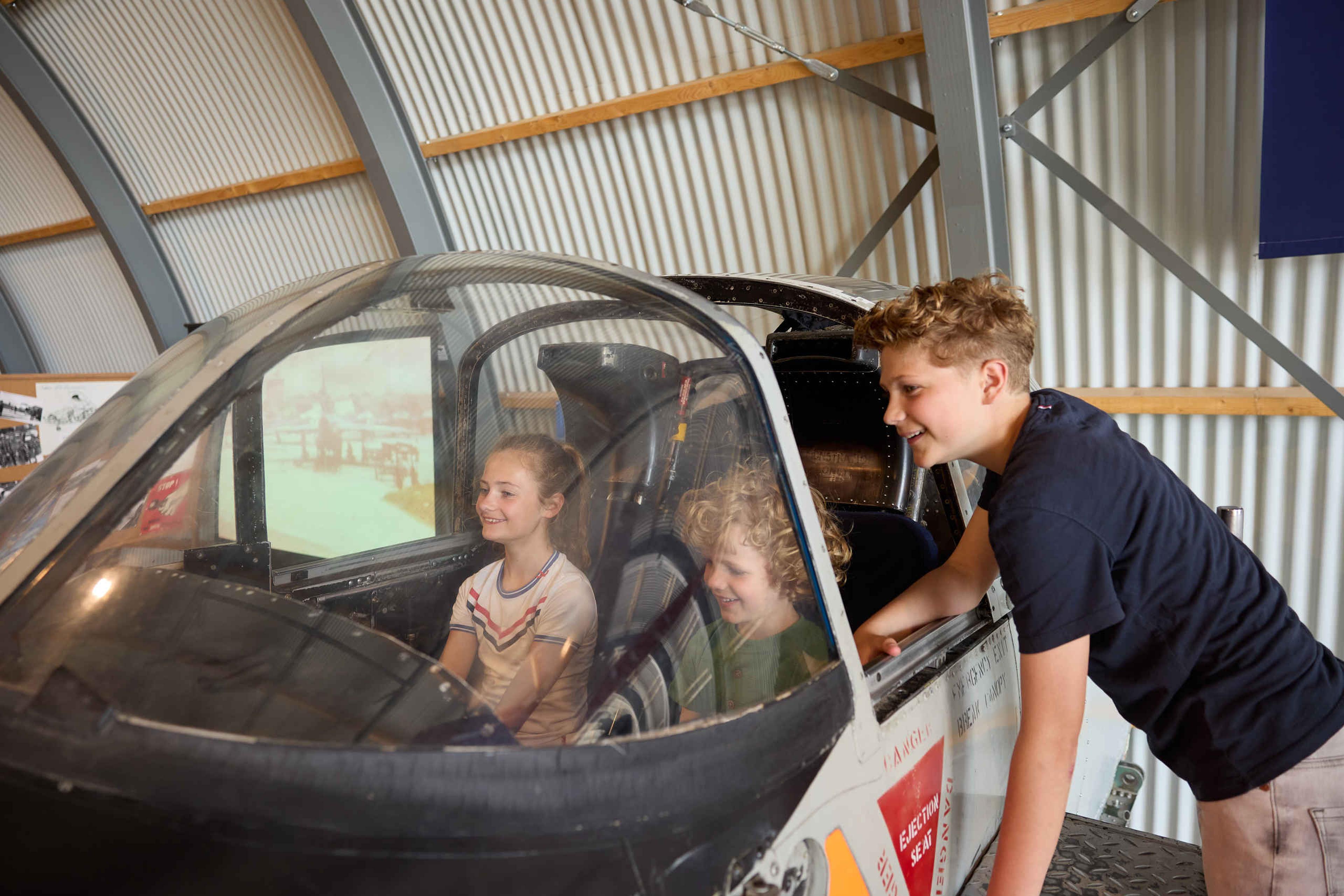 Kinderen zitten in de cockpit van een vliegsimulator bij Luchtvaartmuseum Aviodrome