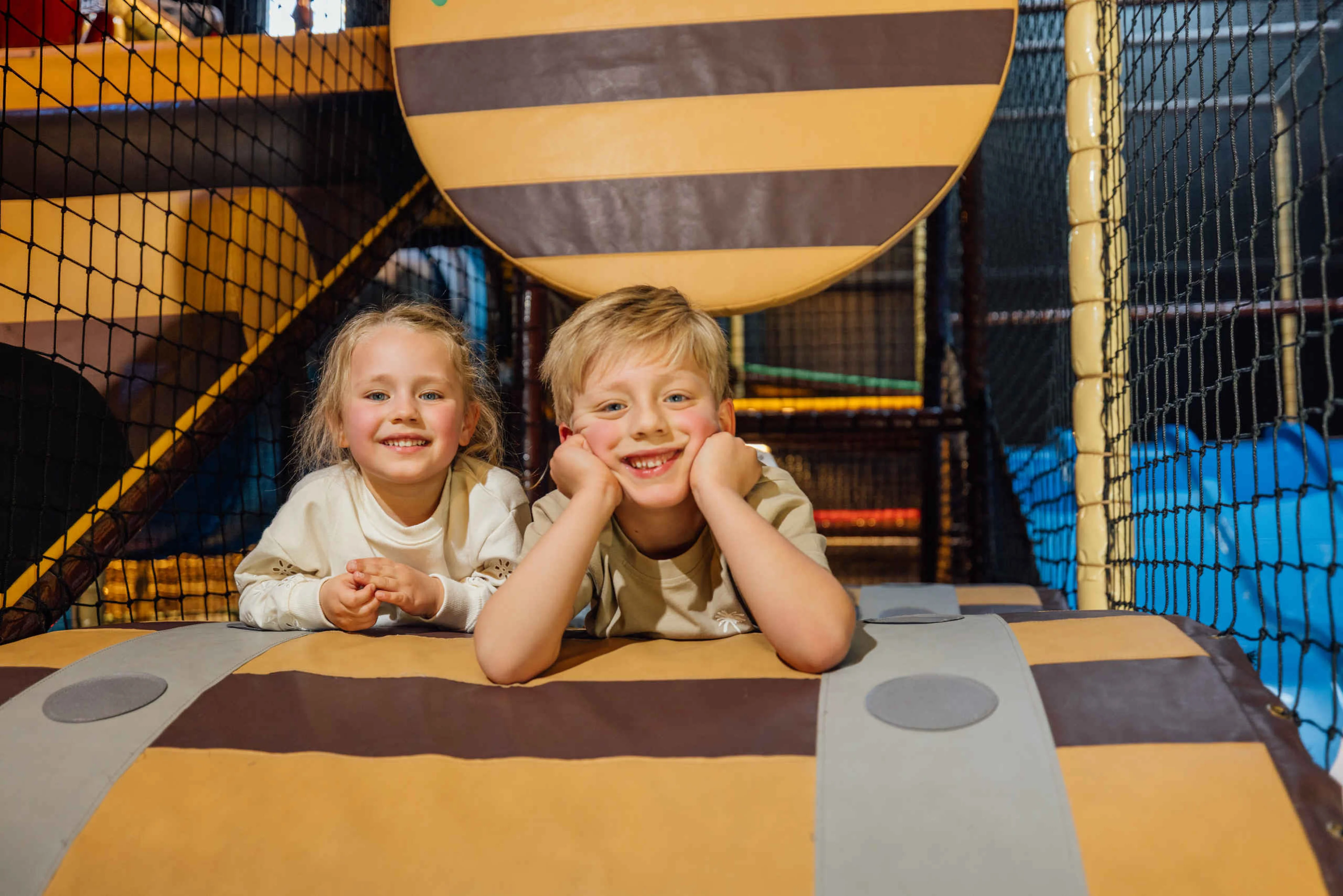 Twee kinderen liggen tussen de hindernissen in Speelland Indoor