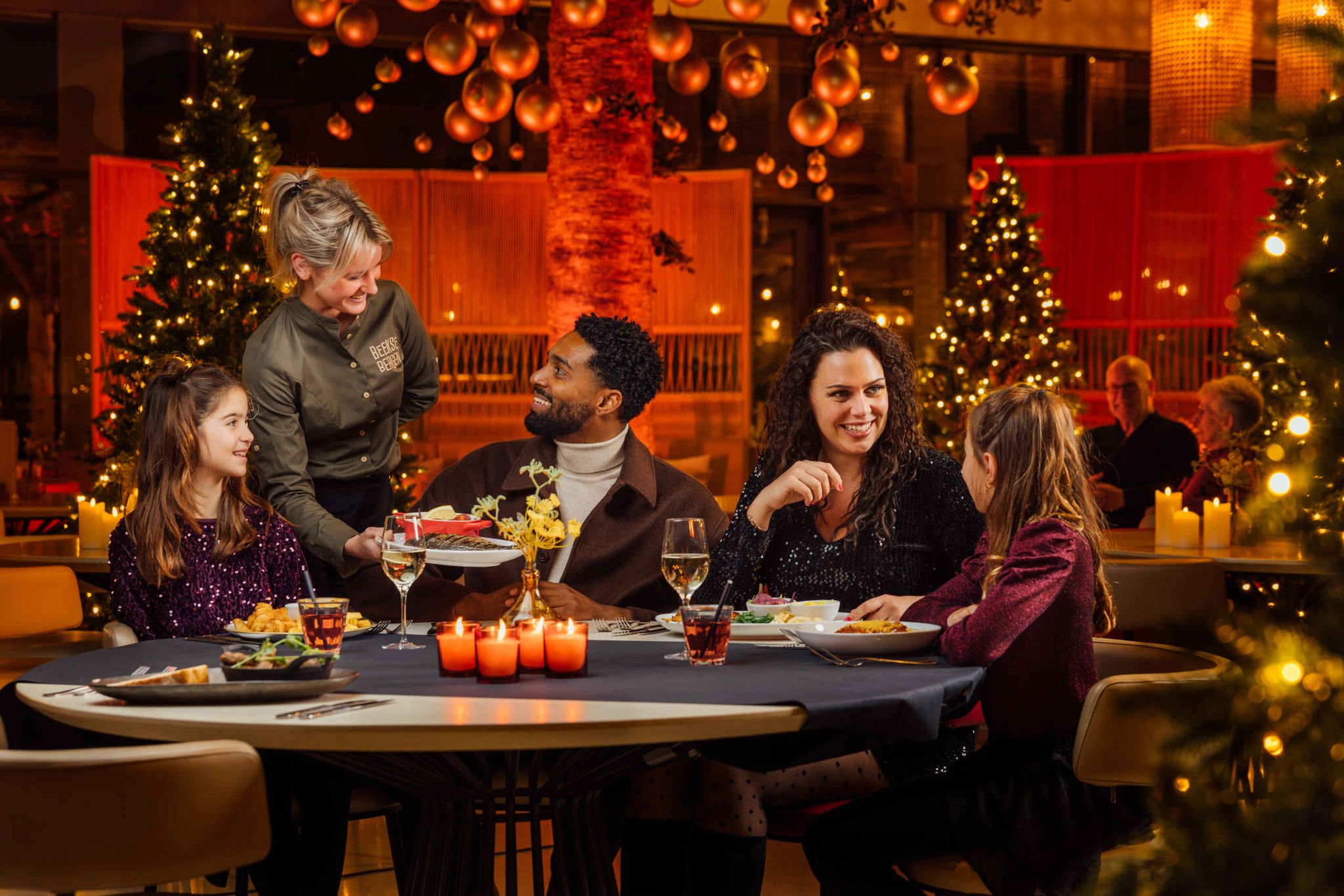Gezin tijdens kerst aan het dineren bij de kerstbomen in restaurant Labadi in Beekse Bergen