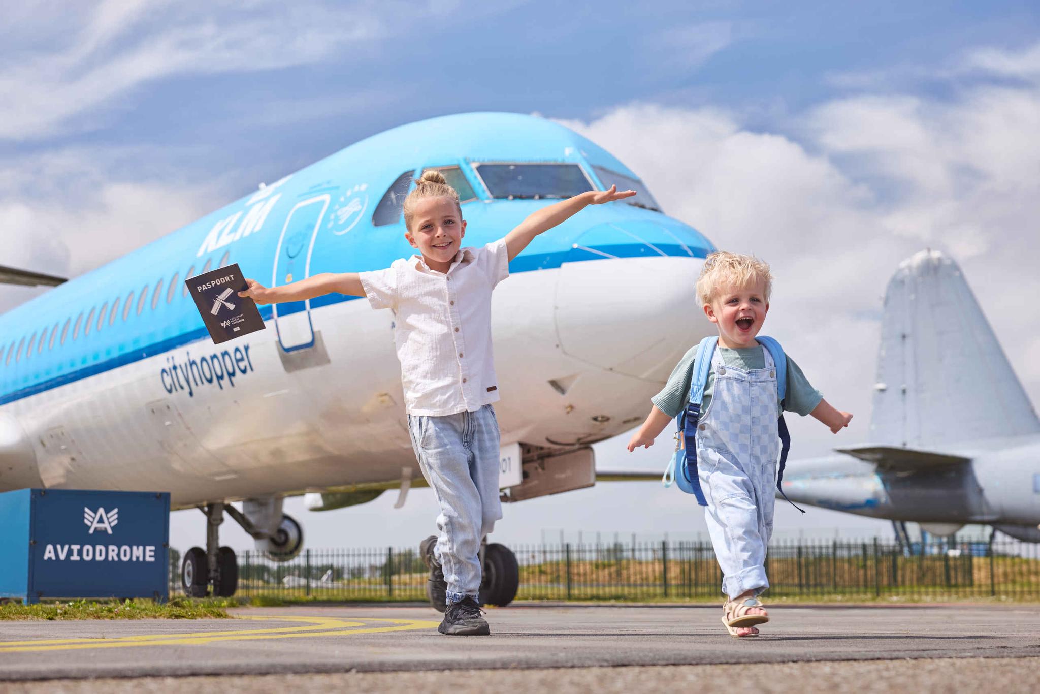 Een rennende kinderen op het buitenterrein van Aviodrome met een KLM Cityhopper op de achtergrond.