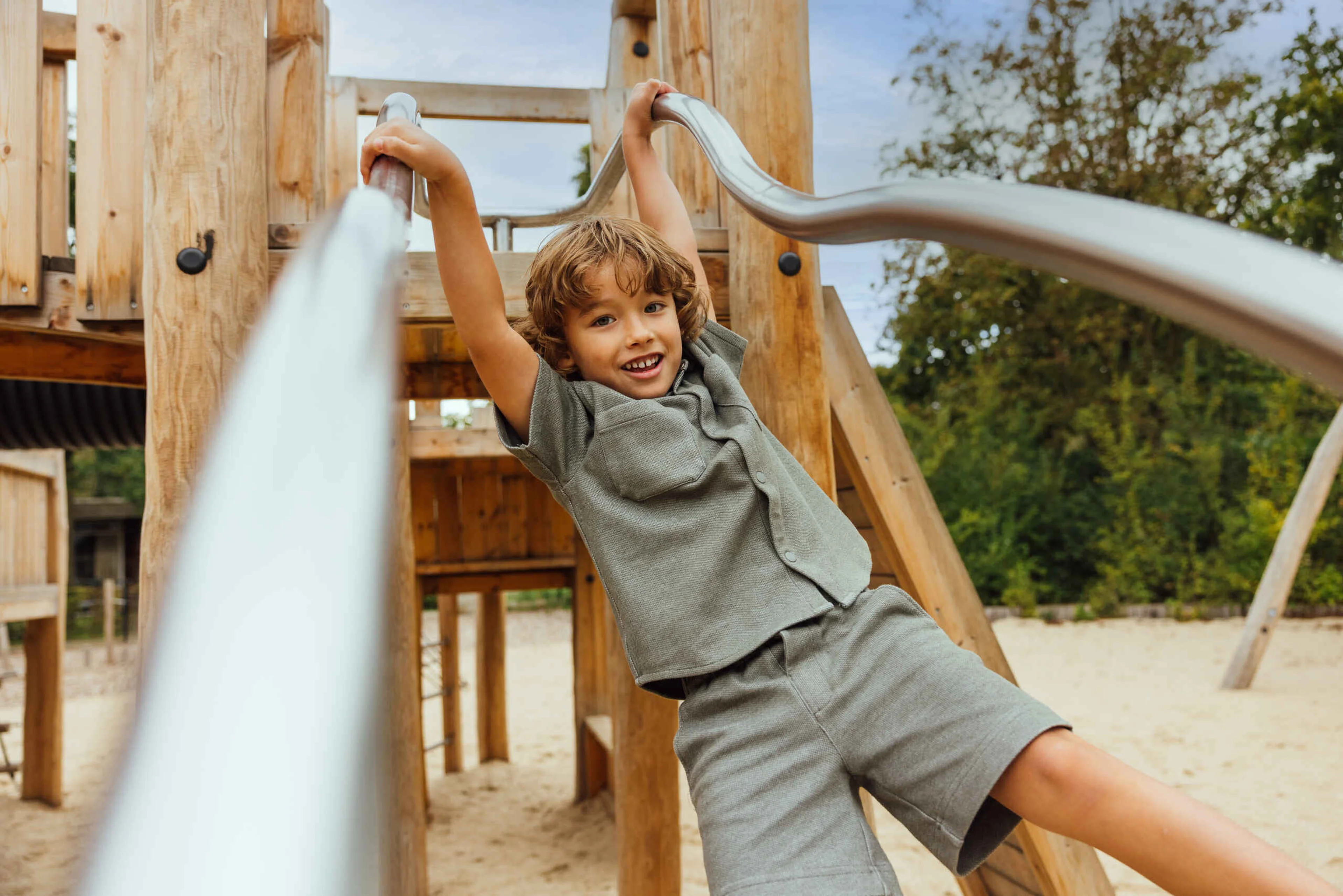 Jongen in speeltuin buiten aan het klimmen op het klimtoestel in Vakantiepark Dierenbos