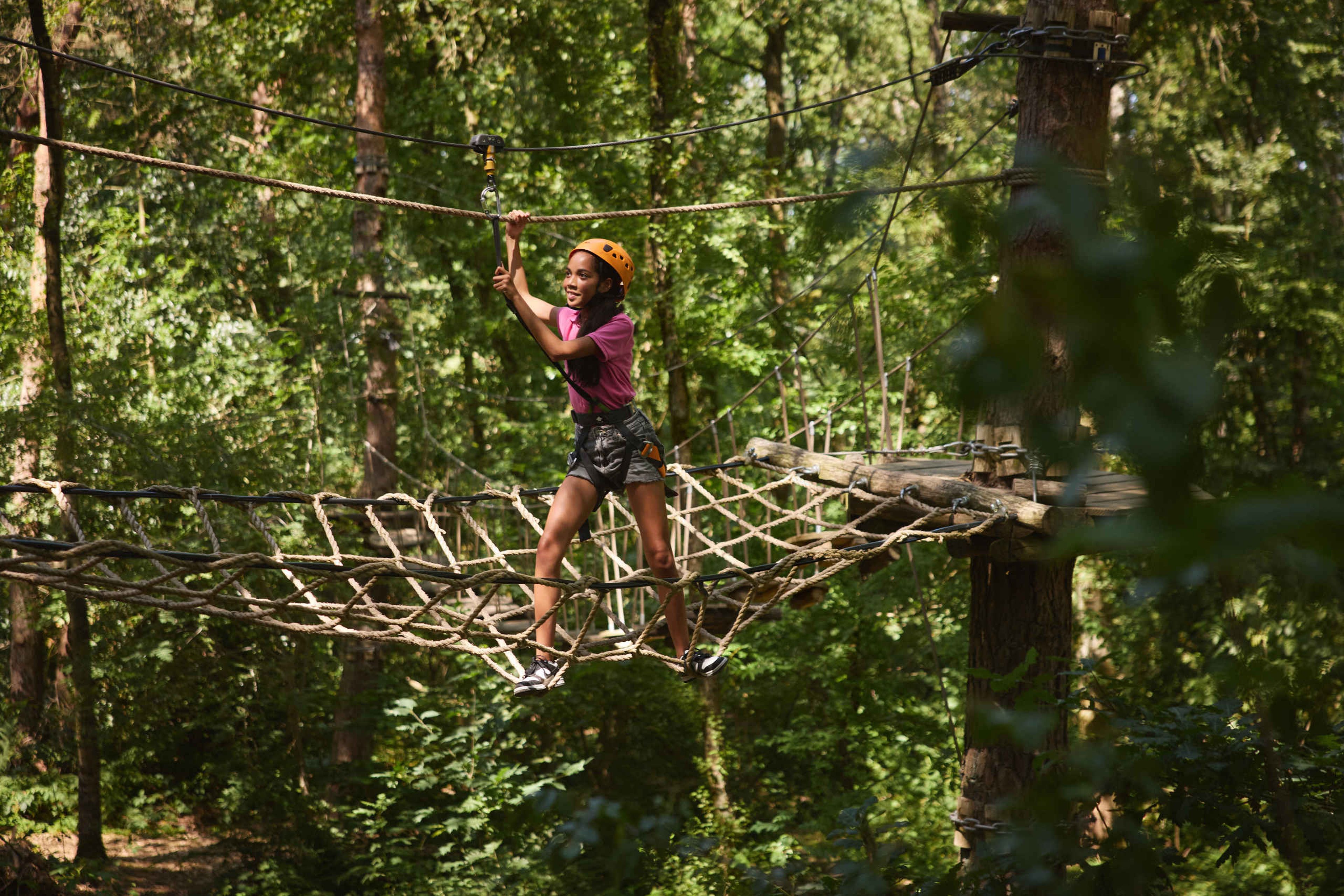 Een meisje op de nettenbrug van het klimparcours bij Klimrijk Brabant