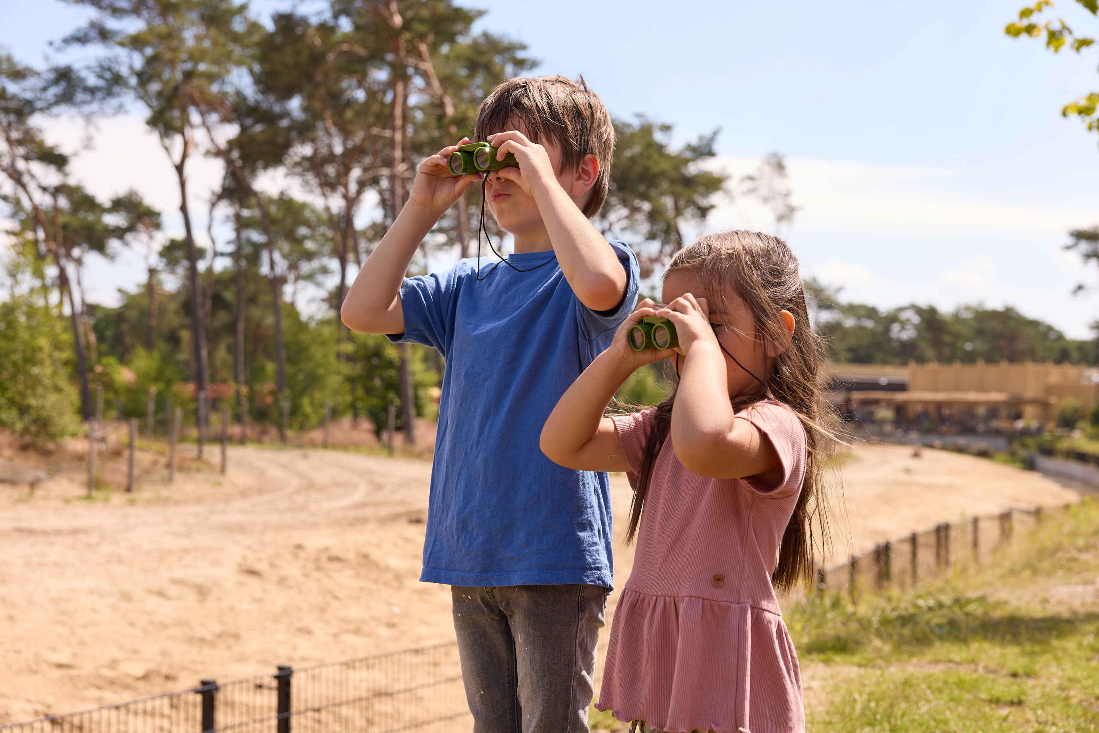 Kinderen een jongen en een meisje bij de savanne met een verrekijker Safaripark Beekse Bergen