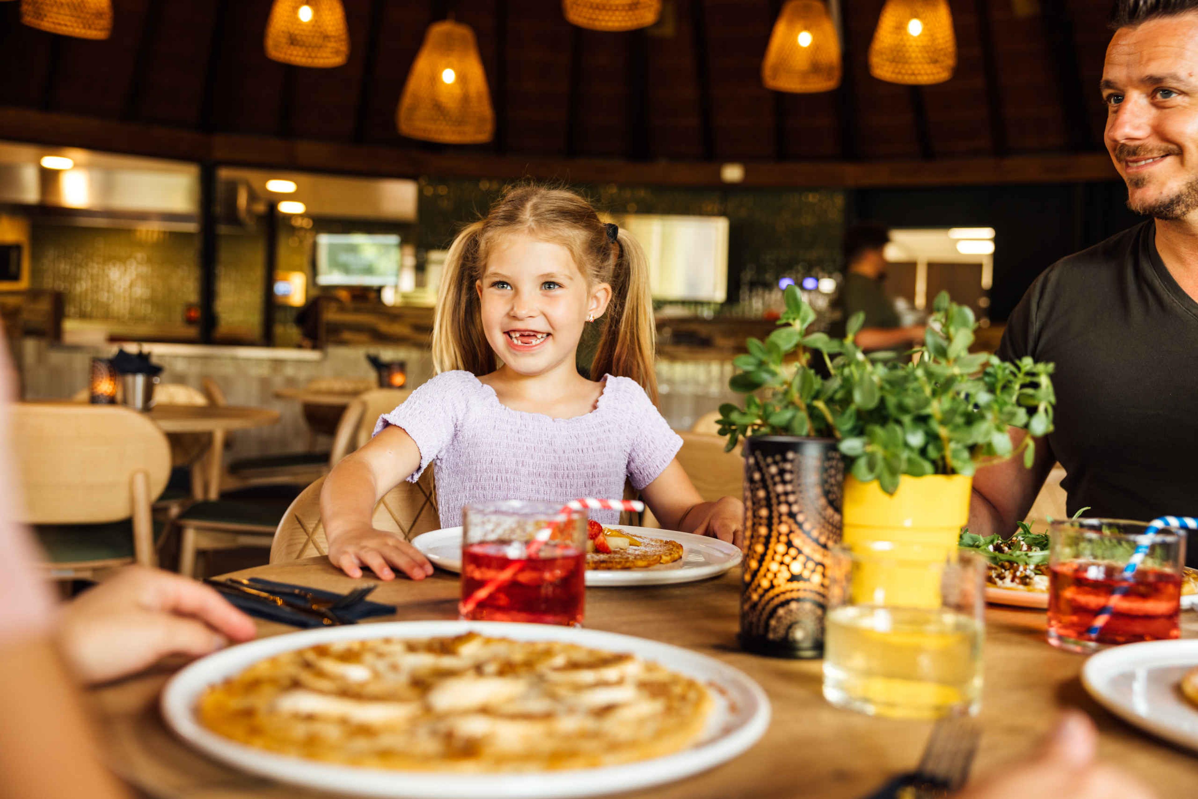 Gezin met vader en dochter eten pannenkoeken in Wanyama in Safaripark Beekse Bergen