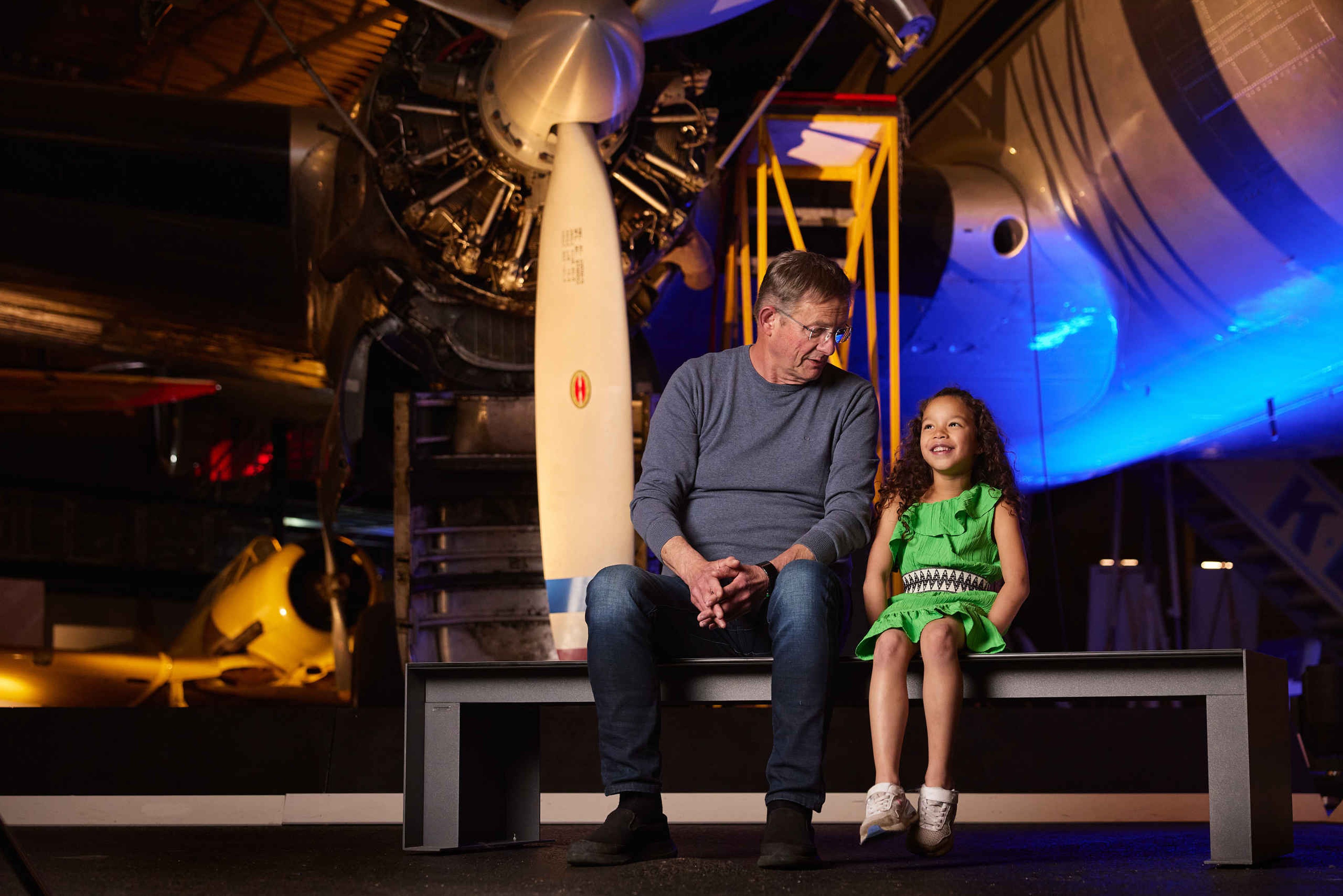 Senior met kind binnen voor vliegtuig tijdens Fly In in Luchtvaartmuseum Aviodrome