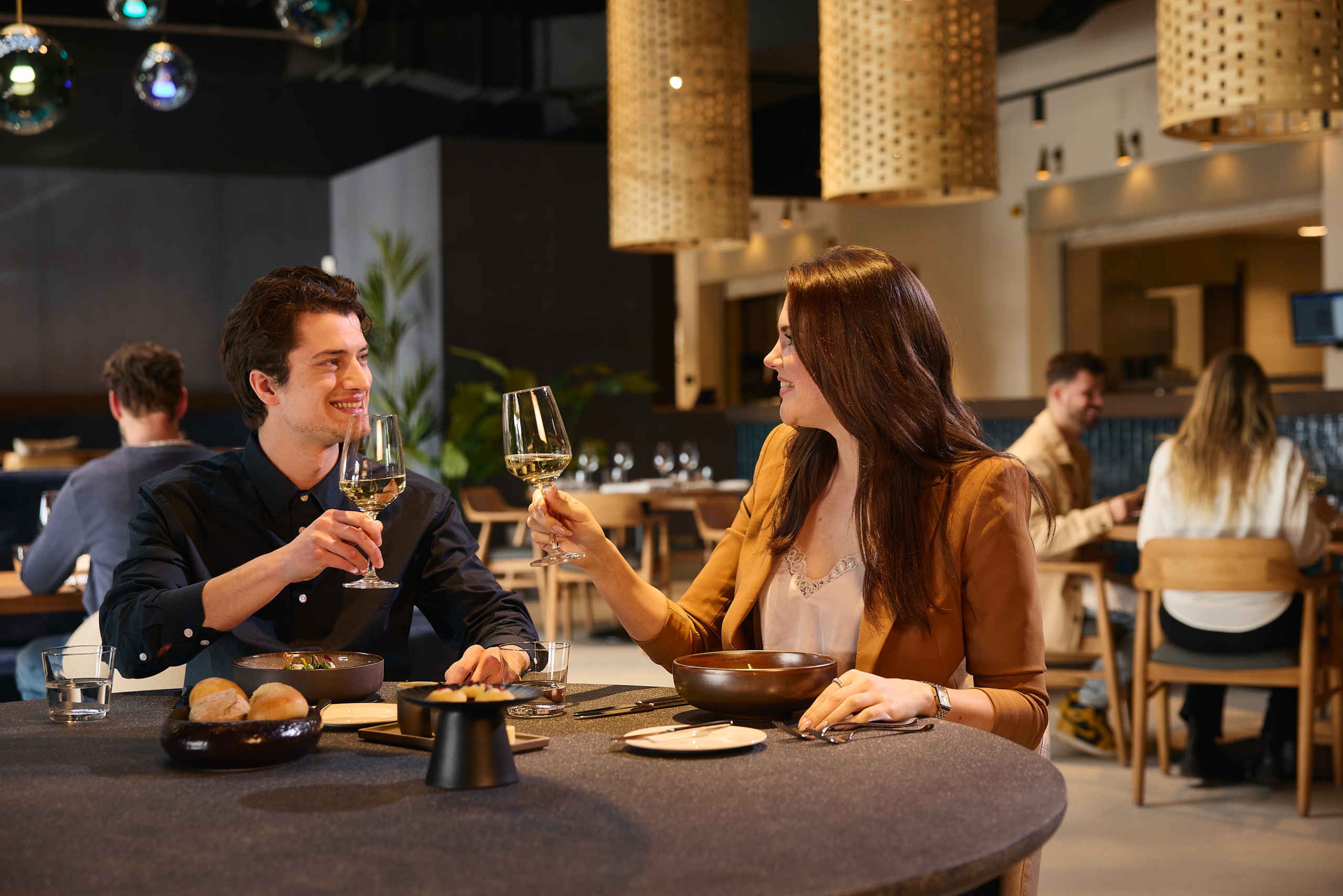 Een koppel dineert en proost met wijn bij Bar & Restaurant Nommos.