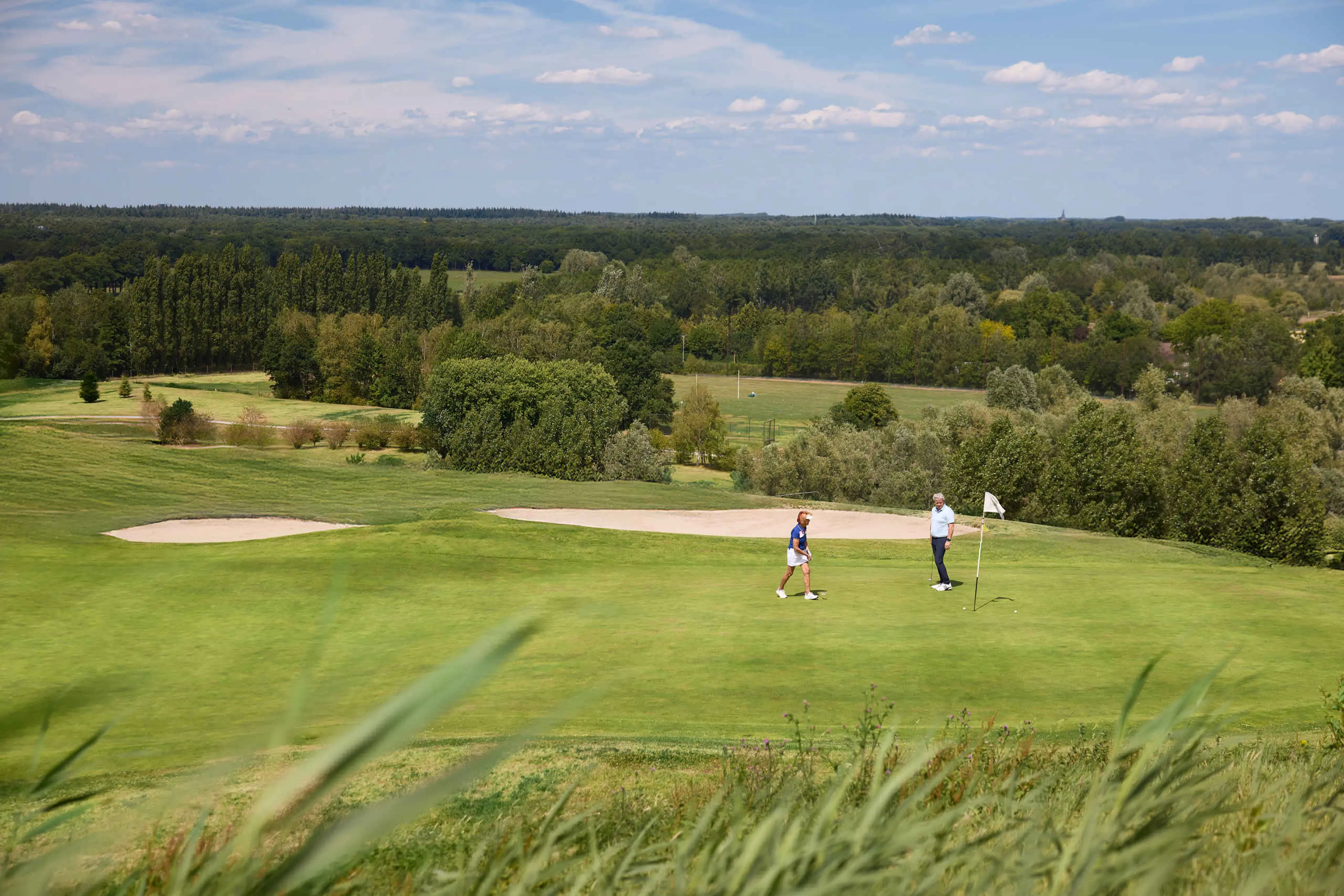 Een man en vrouw staan op de green van hole 2 van de sprookjesbaan bij Golf De Gulbergen