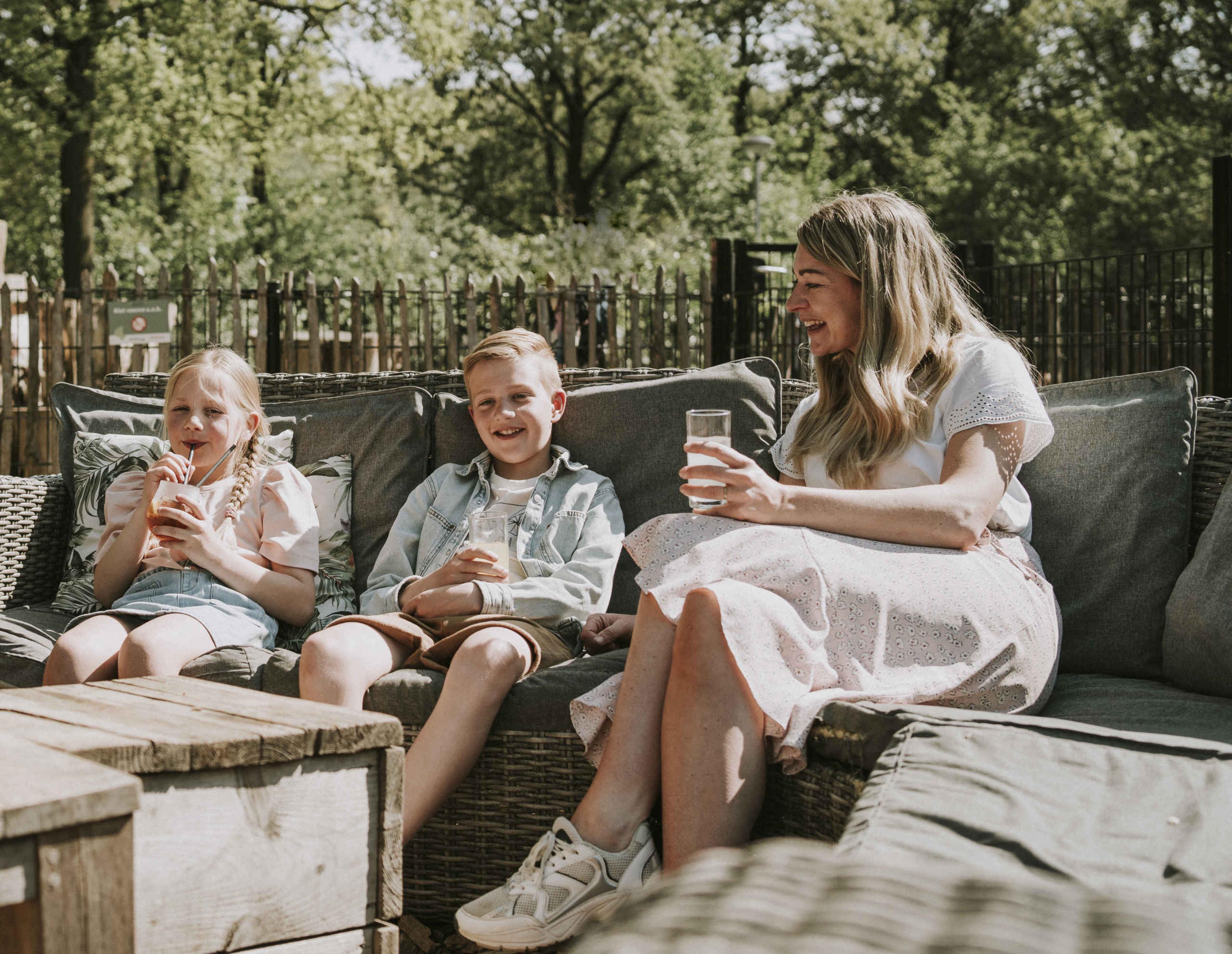 Een moeder en haar kinderen genieten in de zon bij Vakantiepark Dierenbos