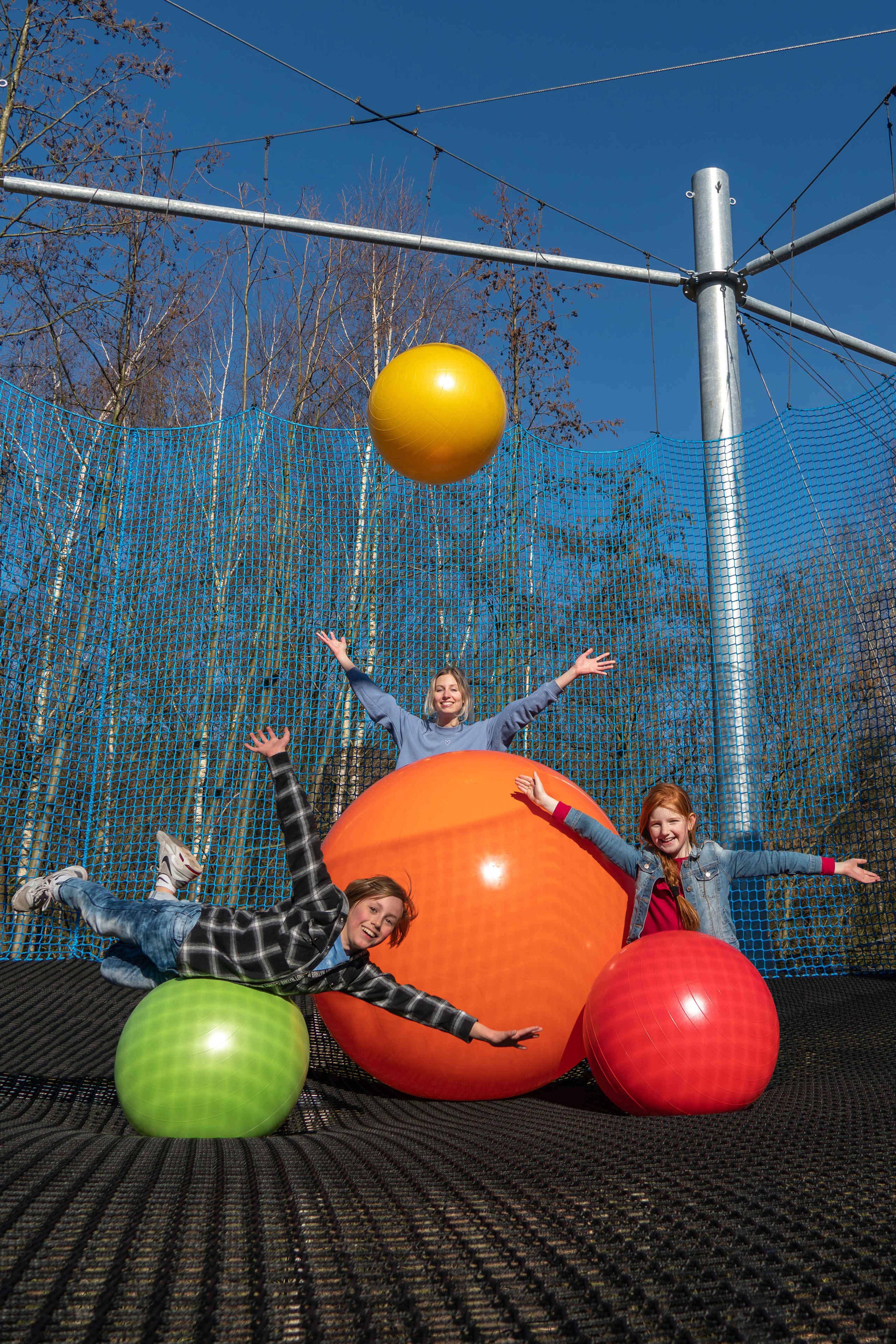 Kinderen en een volwassene met de grote ballen in het Netten Adventure in Klimrijk Brabant