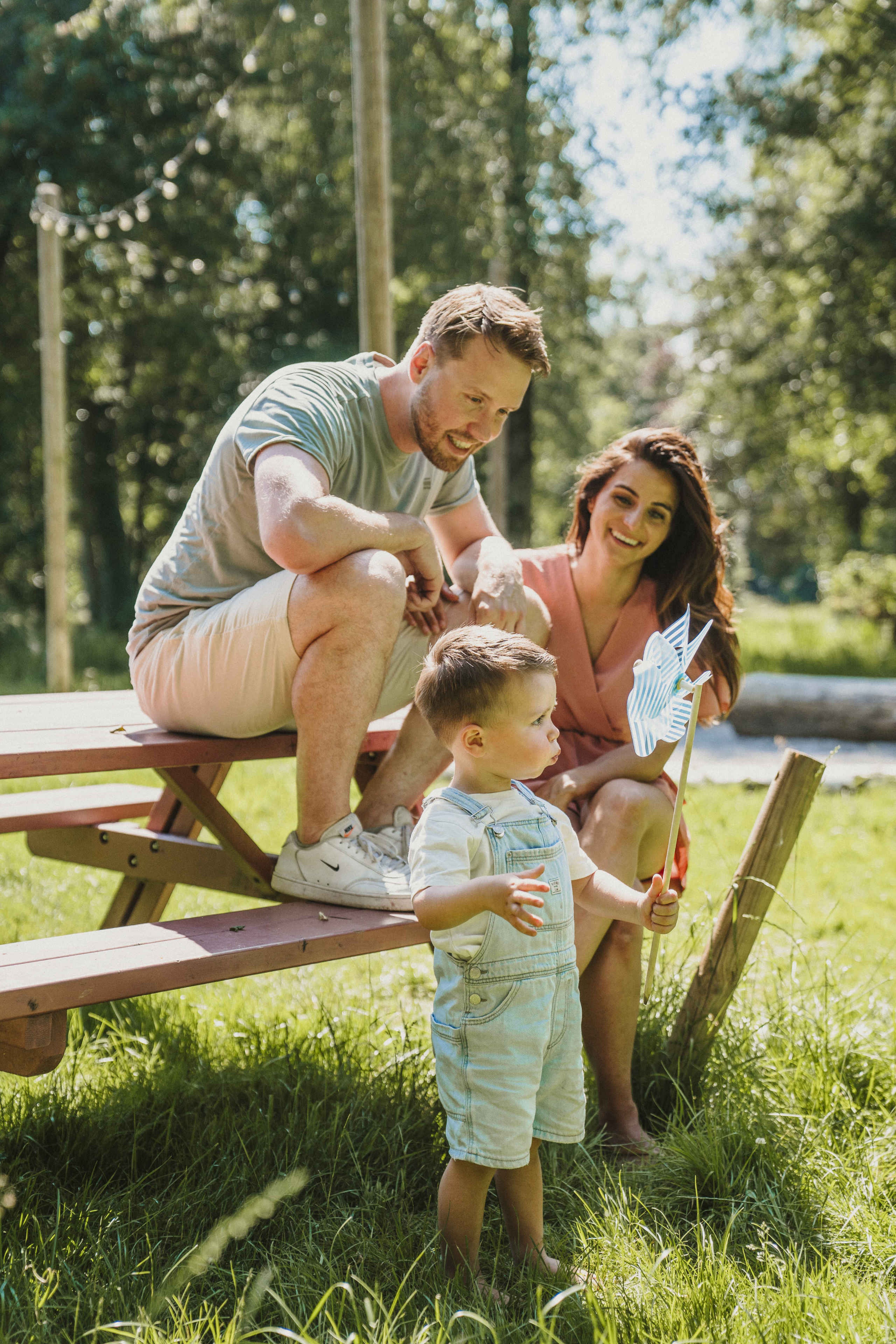 Een moeder en vader lachen met hun zoon Twee kinderen spelen in het gras bij belevingscamping Vuurvlinder bij Vakantiepark Dierenbos