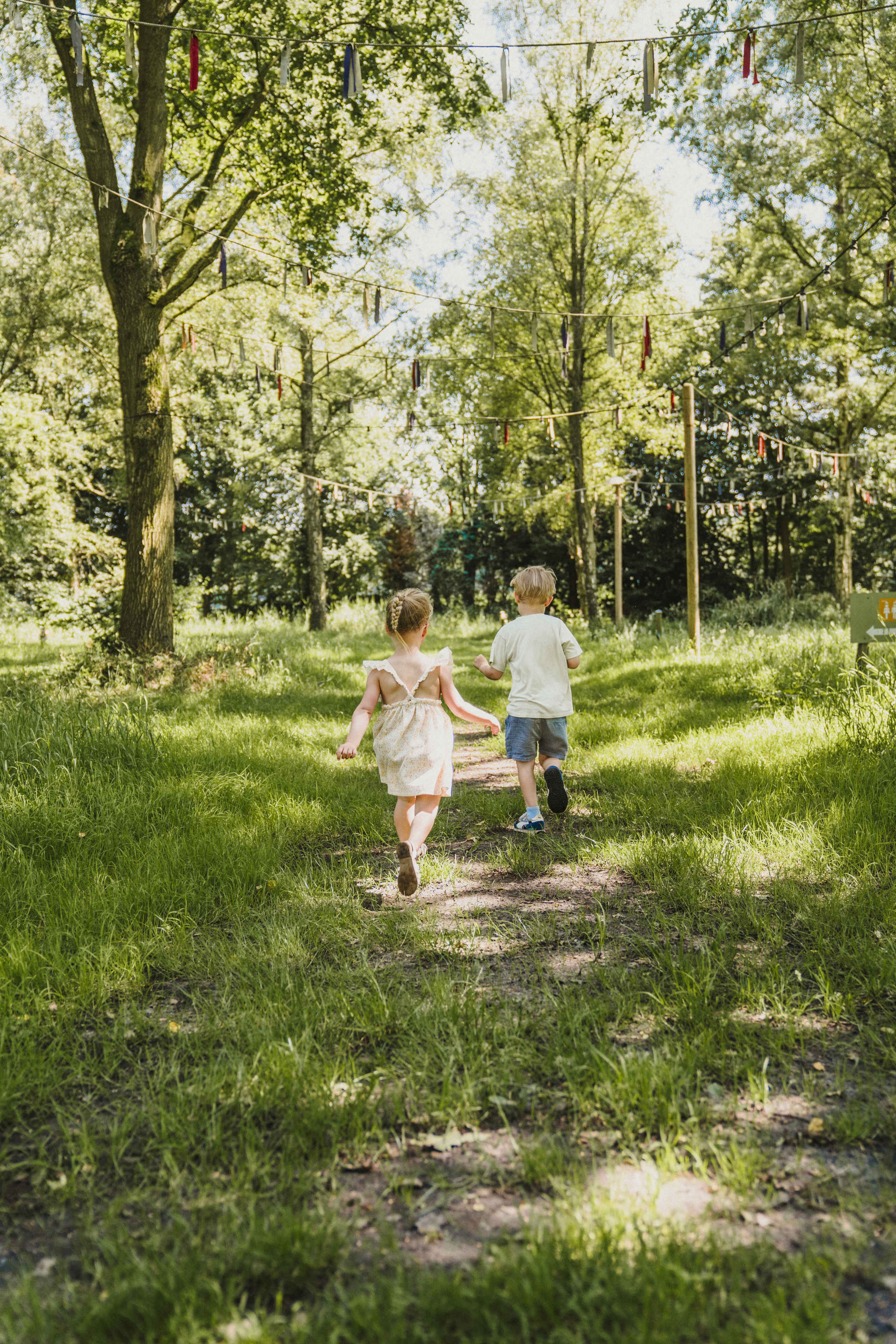 Twee kinderen rennen door het grasveld  bij belevingscamping Vuurvlinder bij Vakantiepark Dierenbos