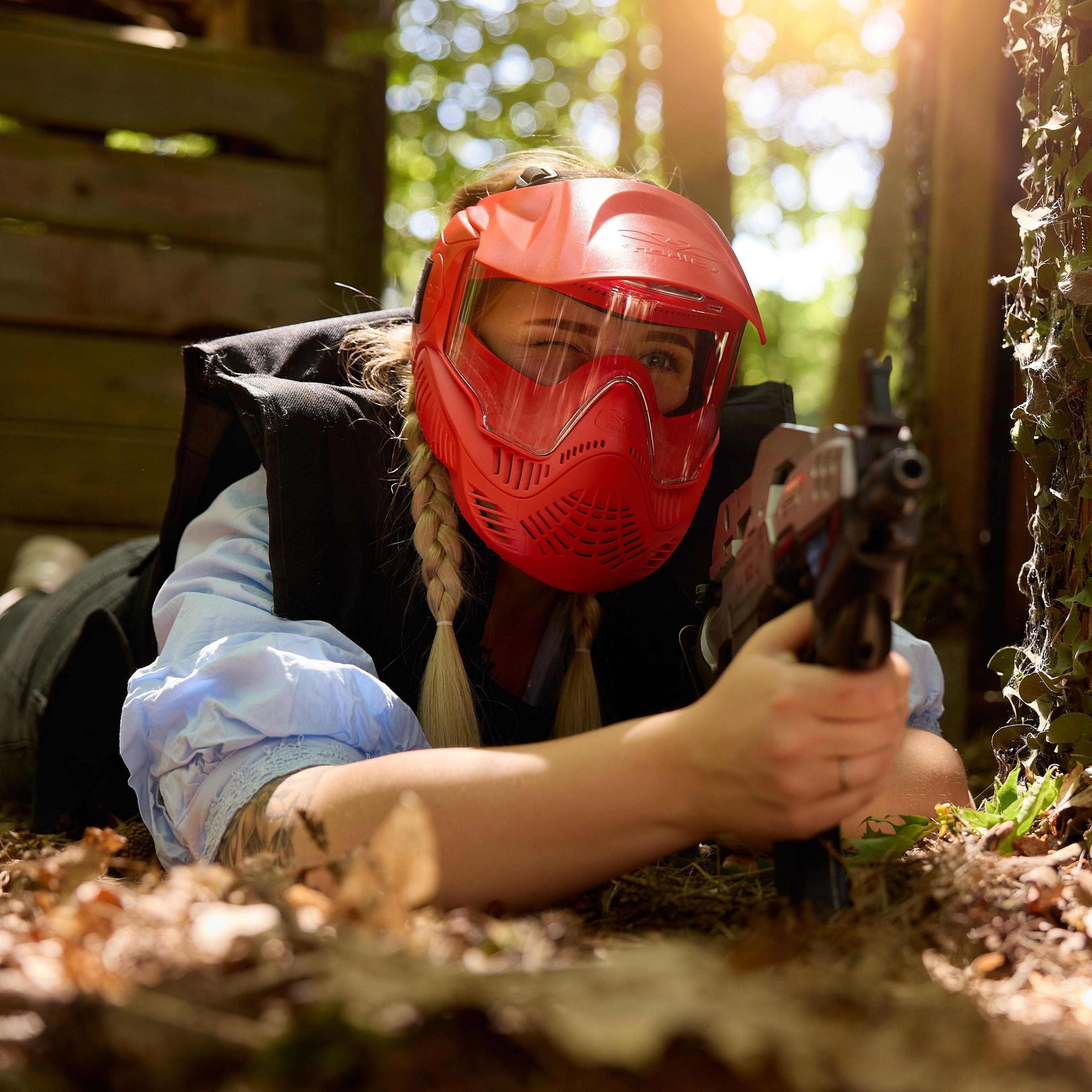 Een vrouw ligt op de grond te schuilen tijdens het airsoften bij Klimrijk Brabant.