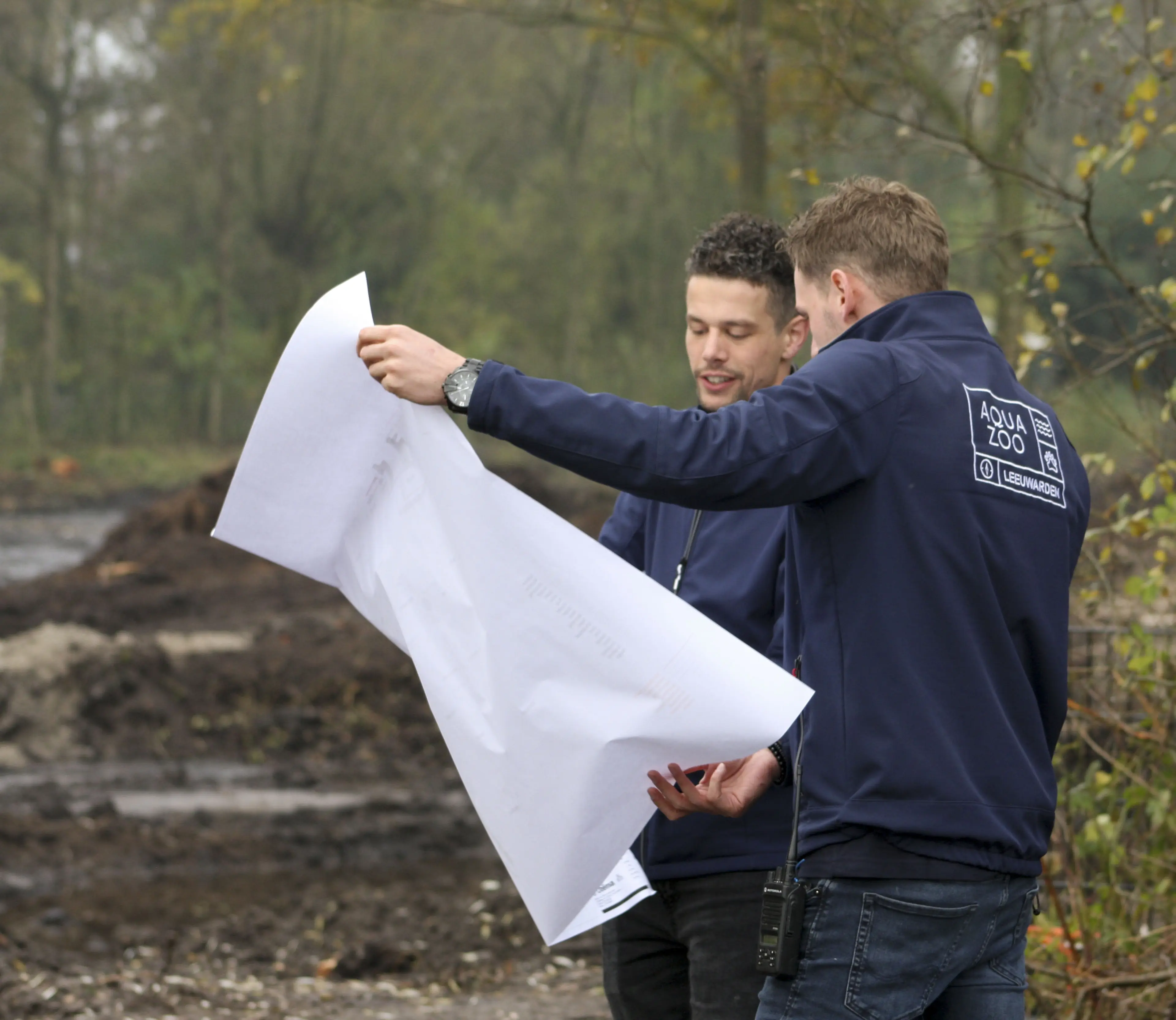 Twee collega's van bouw en onderhoud bekijken een bouwontwerp