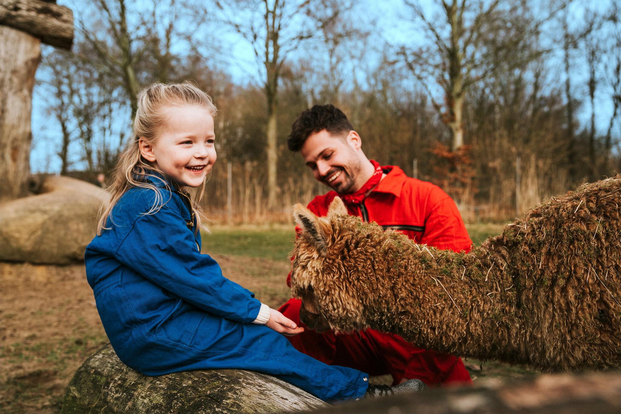 Een meisje en dierenverzorger bij de alpaca op vakantiepark Dierenbos.