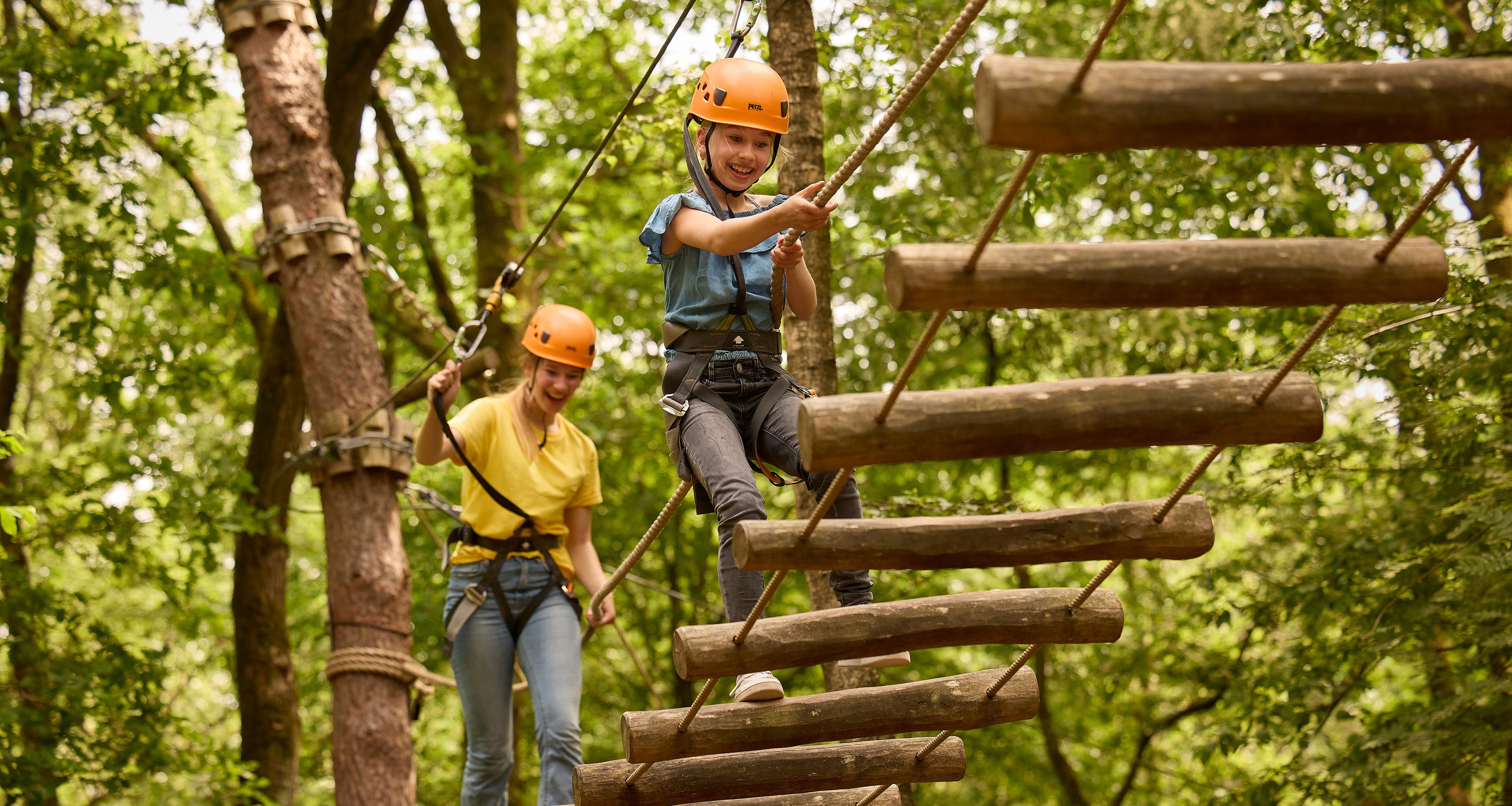 Kinderen op loopbrug met boomstammen op klimparcours bij Klimrijk Brabant