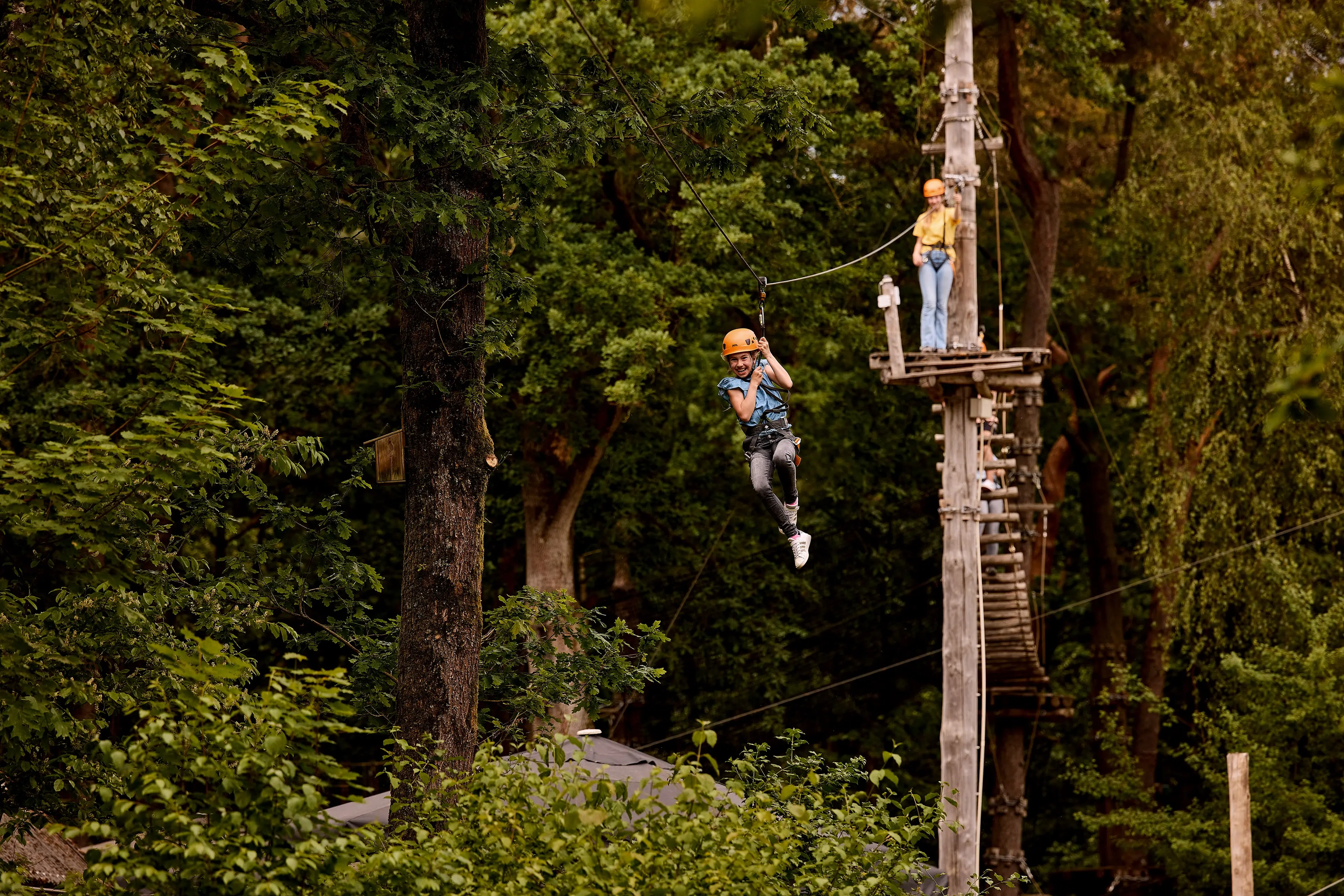 Een meisje gaat van de zipline op het klimparcours bij Klimrijk Brabant.