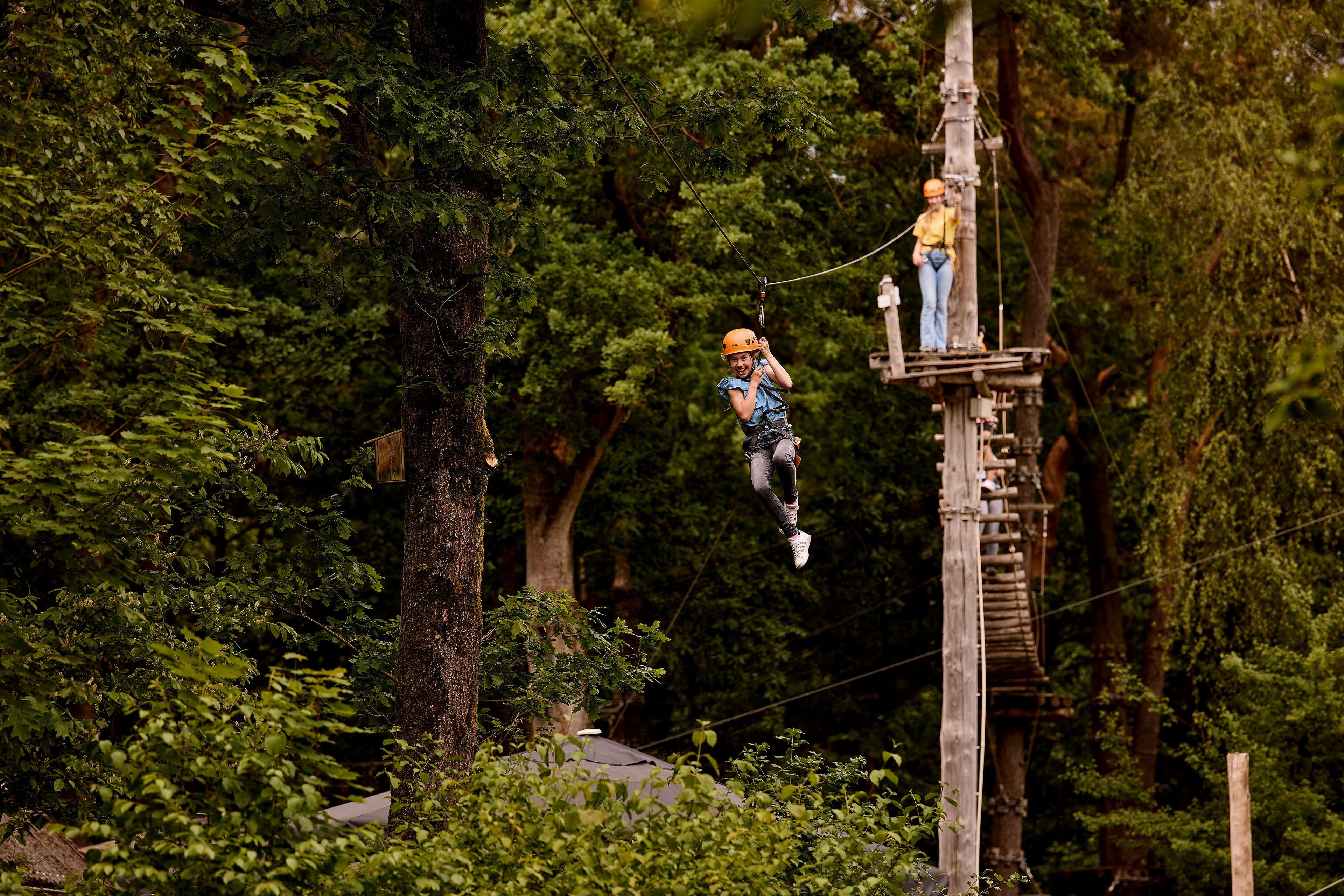 Een meisje gaat van de zipline op het klimparcours bij Klimrijk Brabant.