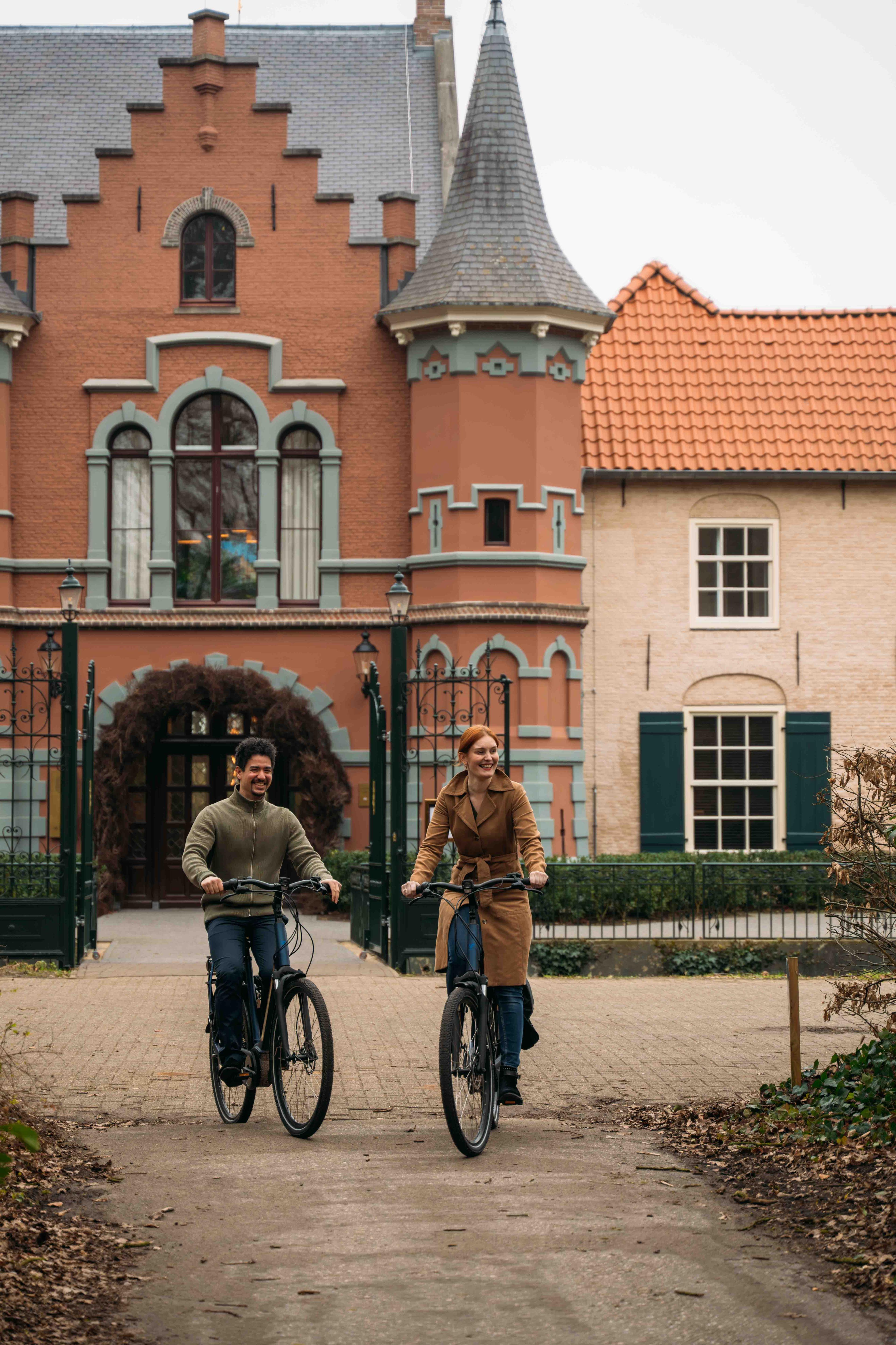 Koppel op de fiets voor de ingang van Kasteel Steenenburg