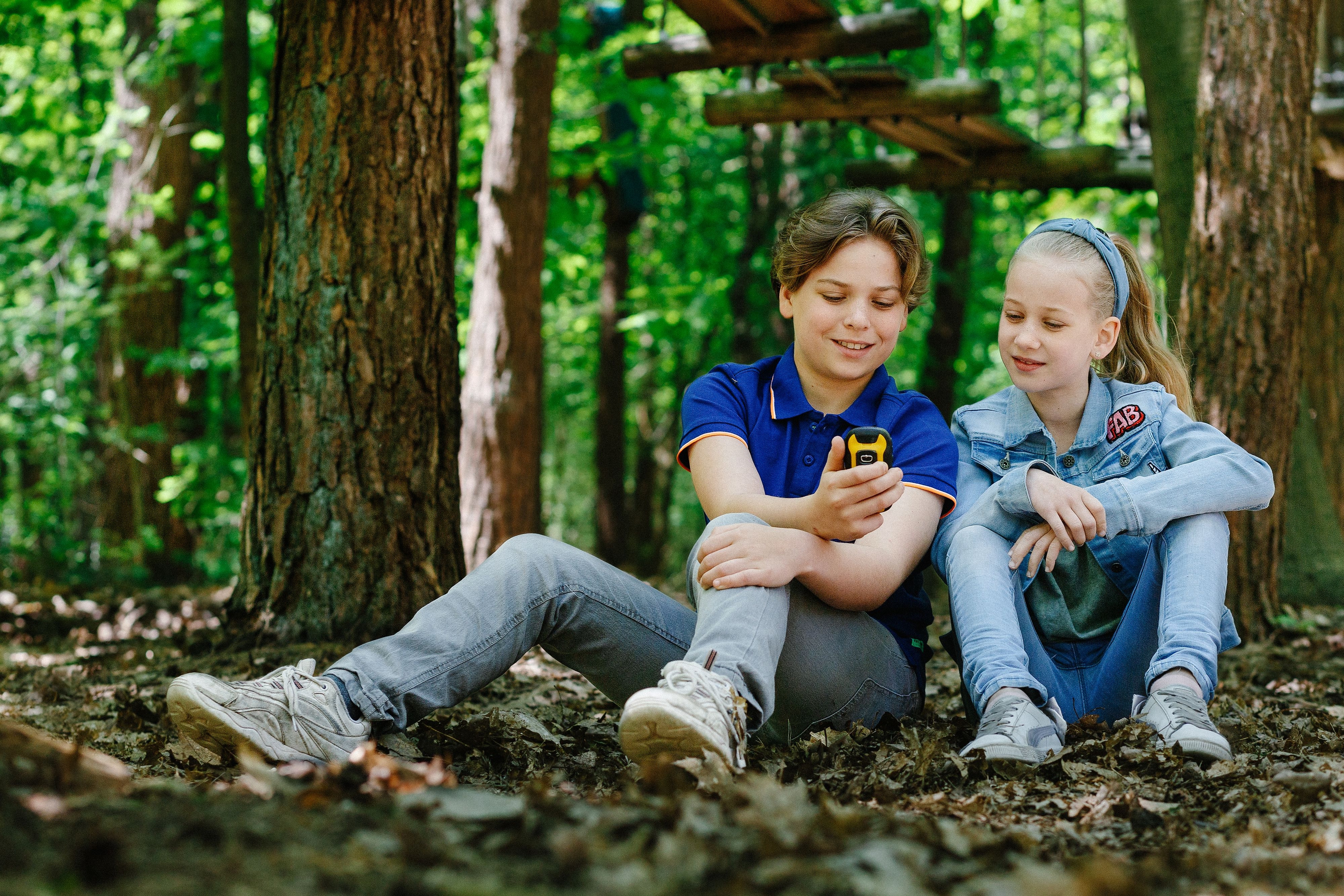 Jongen en meisje zitten met gps tijdens gps-wandeltocht bij Klimrijk Brabant