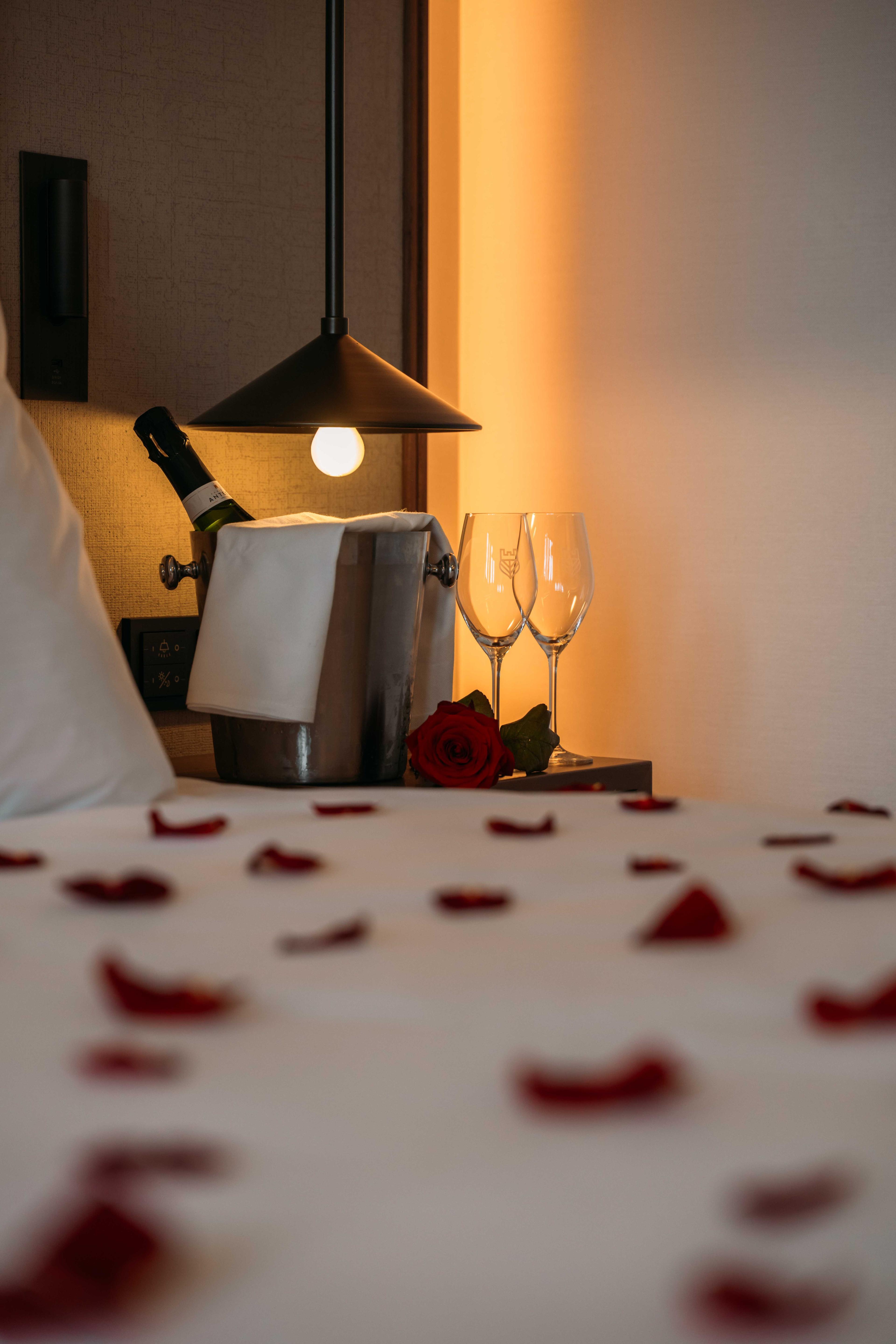 Champagne en rozenblaadjes bij een bed in Kasteel Steenenburg