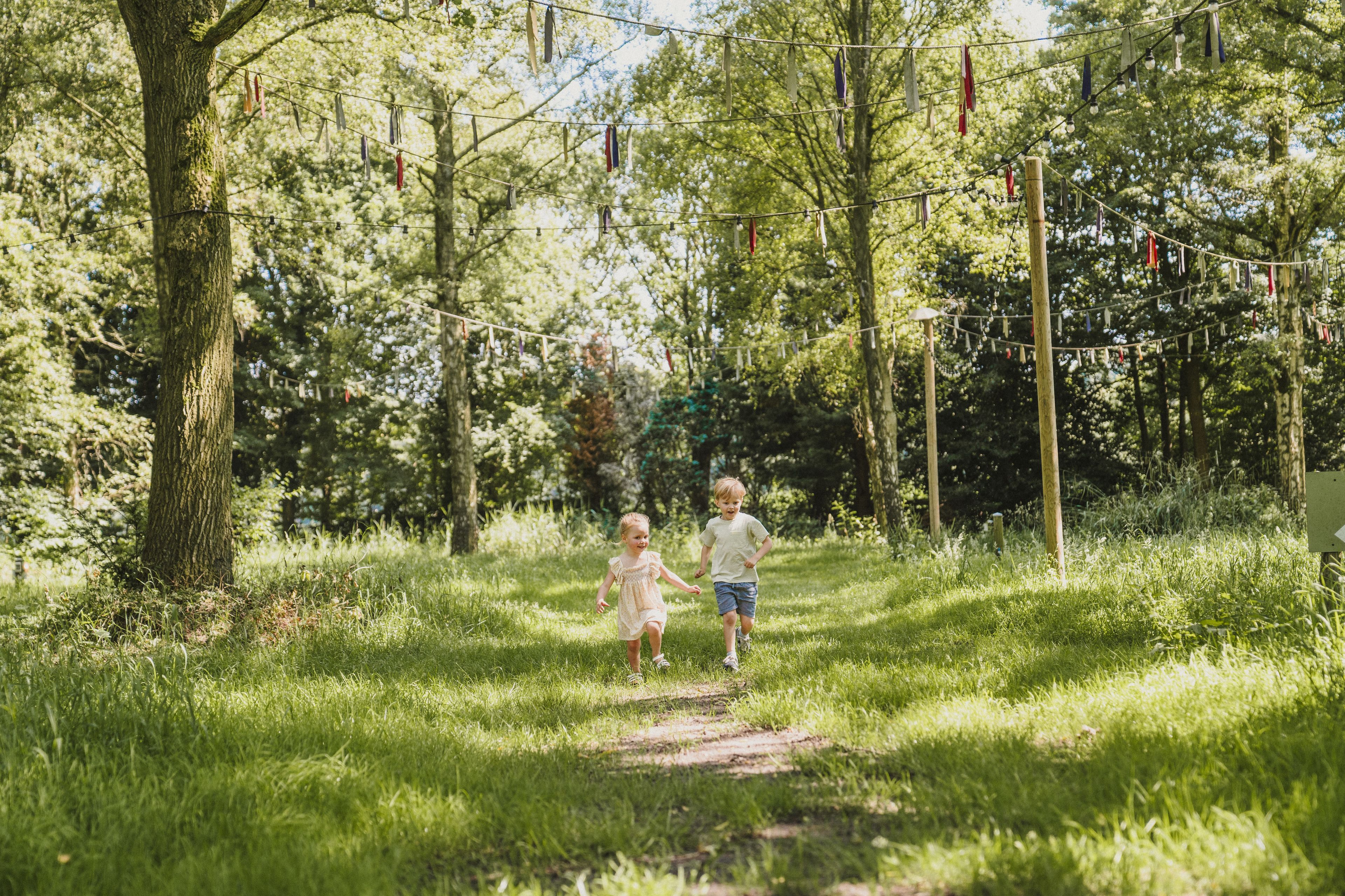 Twee kinderen rennen bij belevingscamping vuurvlinder door het gras