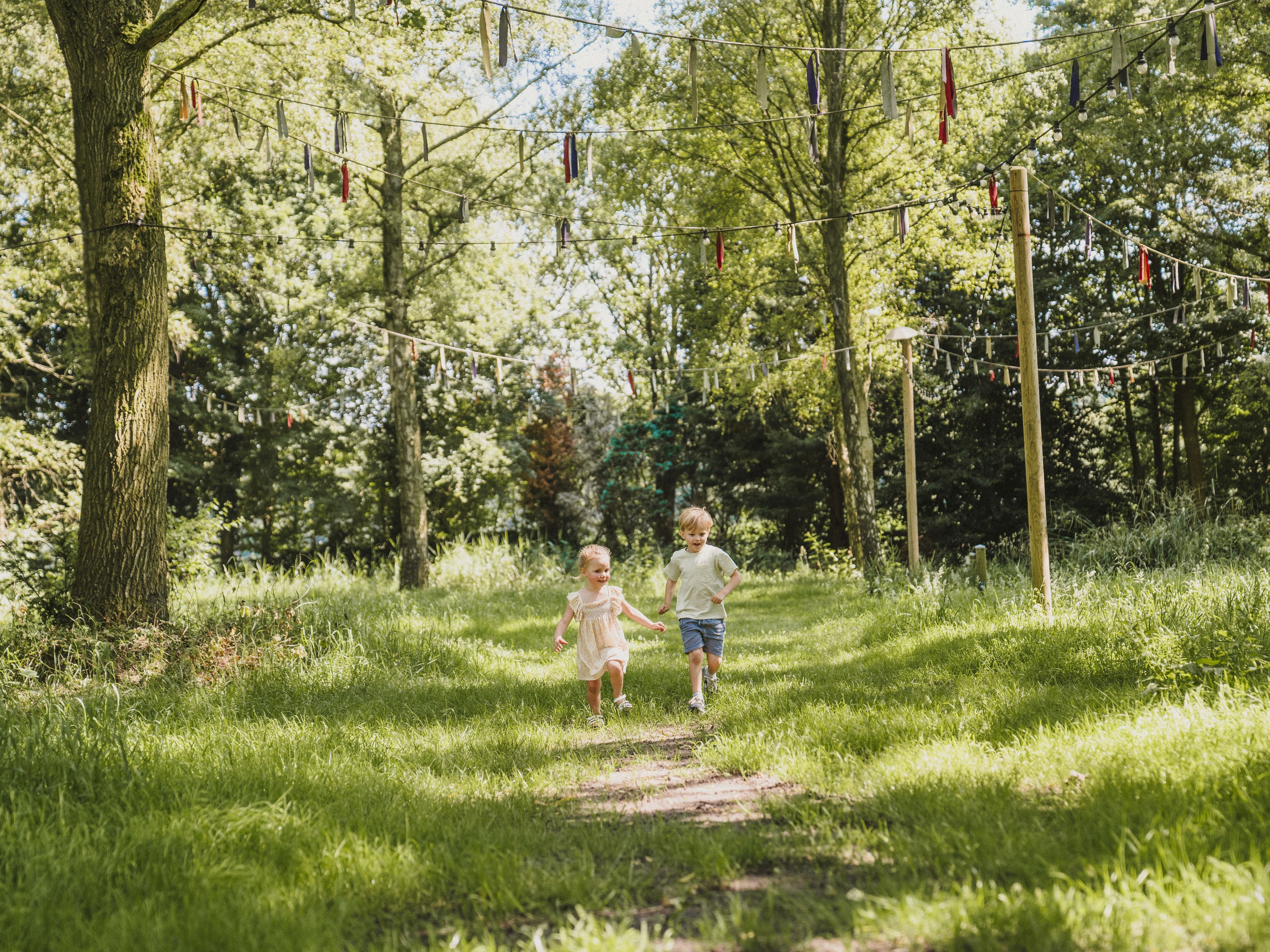 Twee kinderen rennen bij belevingscamping vuurvlinder door het gras