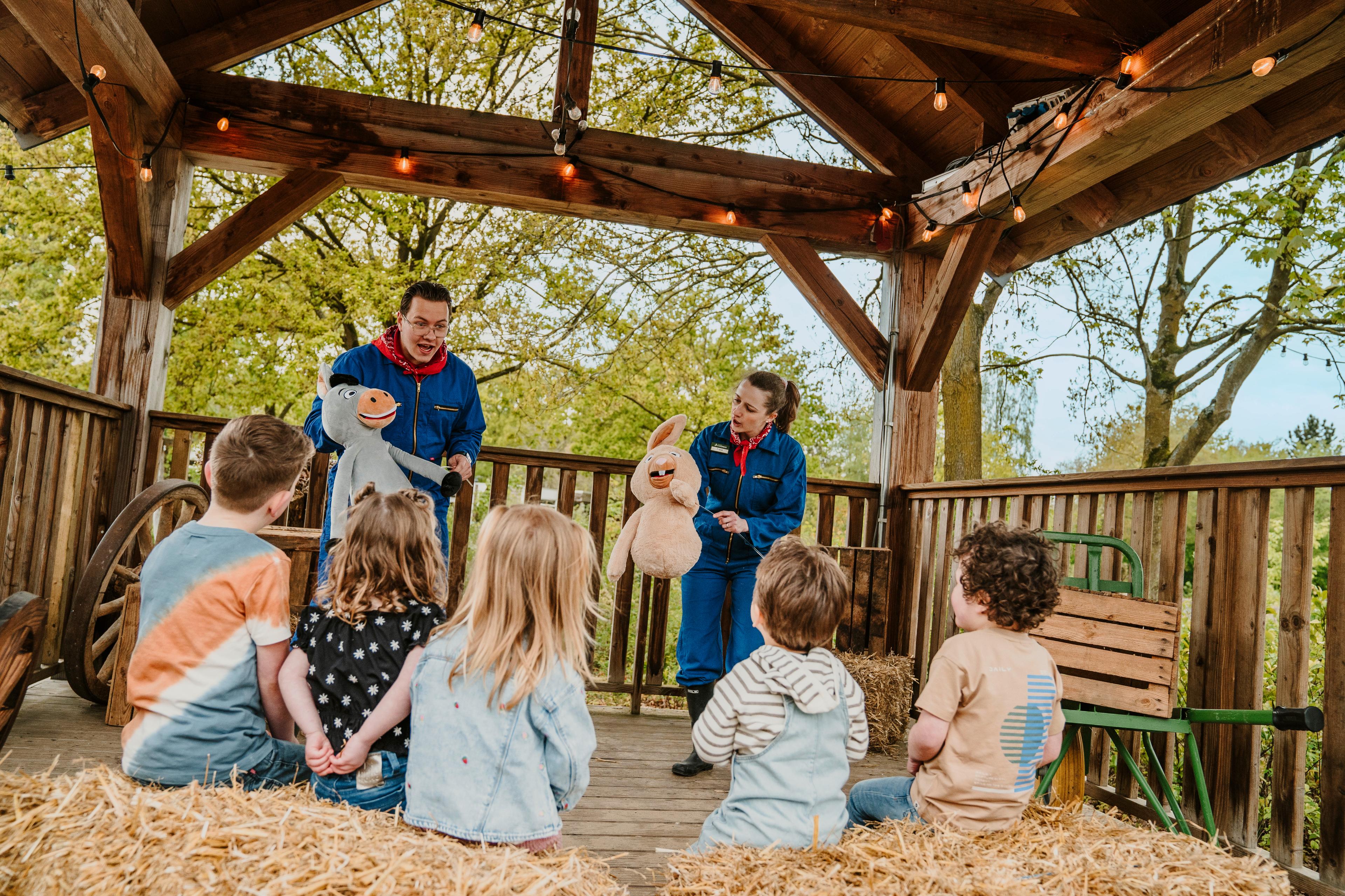 Het animatieteam geeft een handpoppenshow aan een groep kinderen bij Vakantiepark Dierenbos.