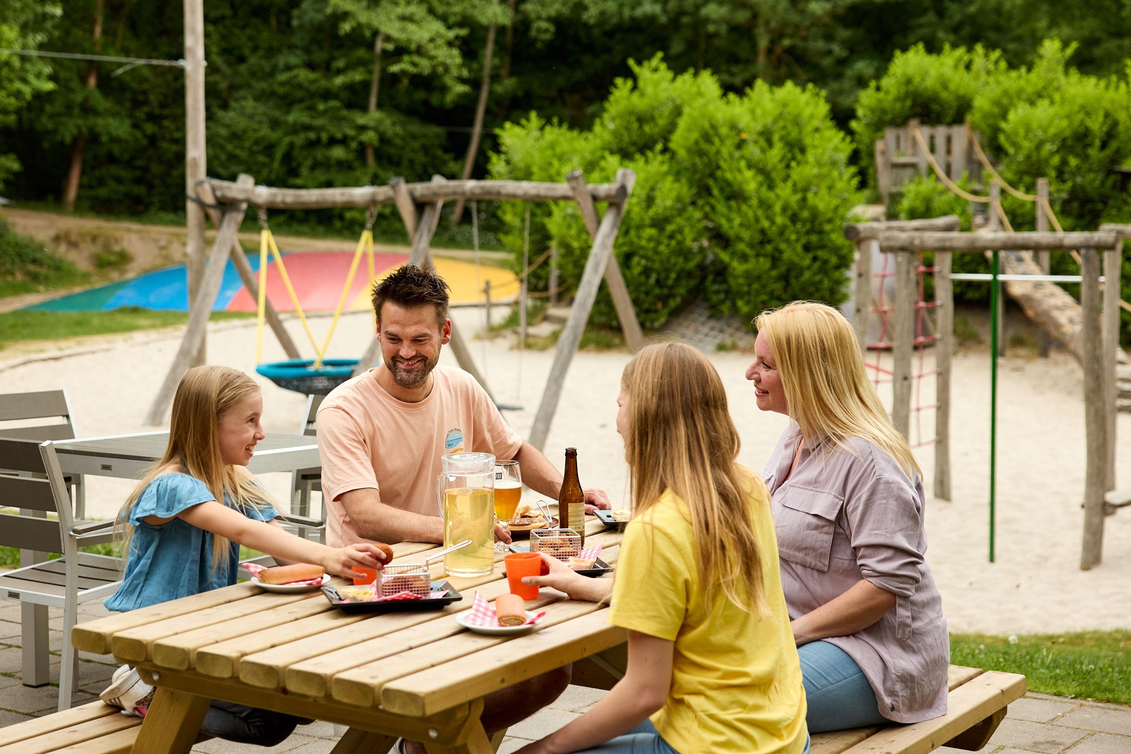 Gezin aan een picknicktafel aan een borrel met hapjes bij Klimrijk Brabant