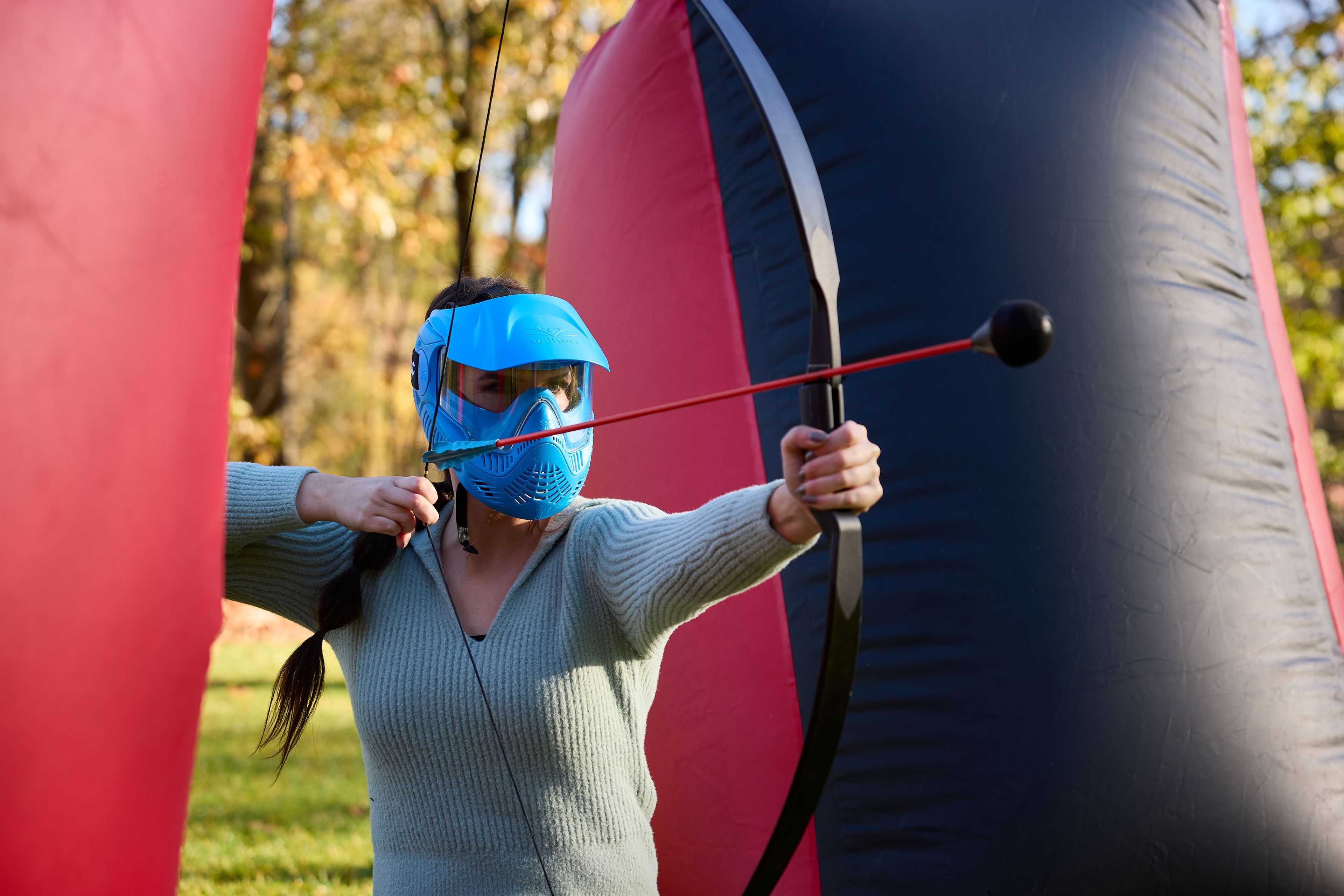 Vrouw schiet een pijl tijdens outdoor archery tag bij Klimrijk Brabant