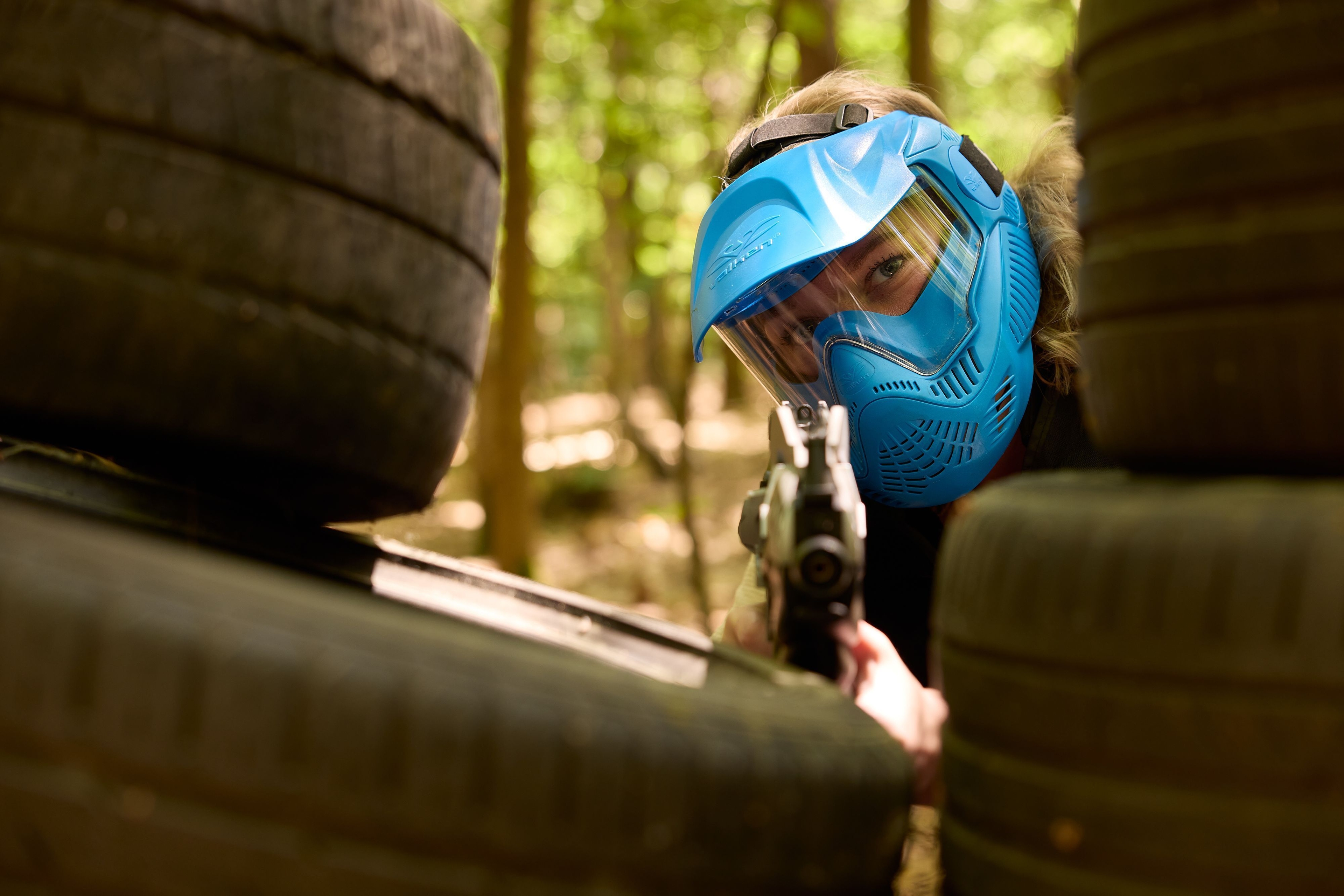 Vrouw tussen stapel banden aan het airsoften bij Klimrijk Brabant