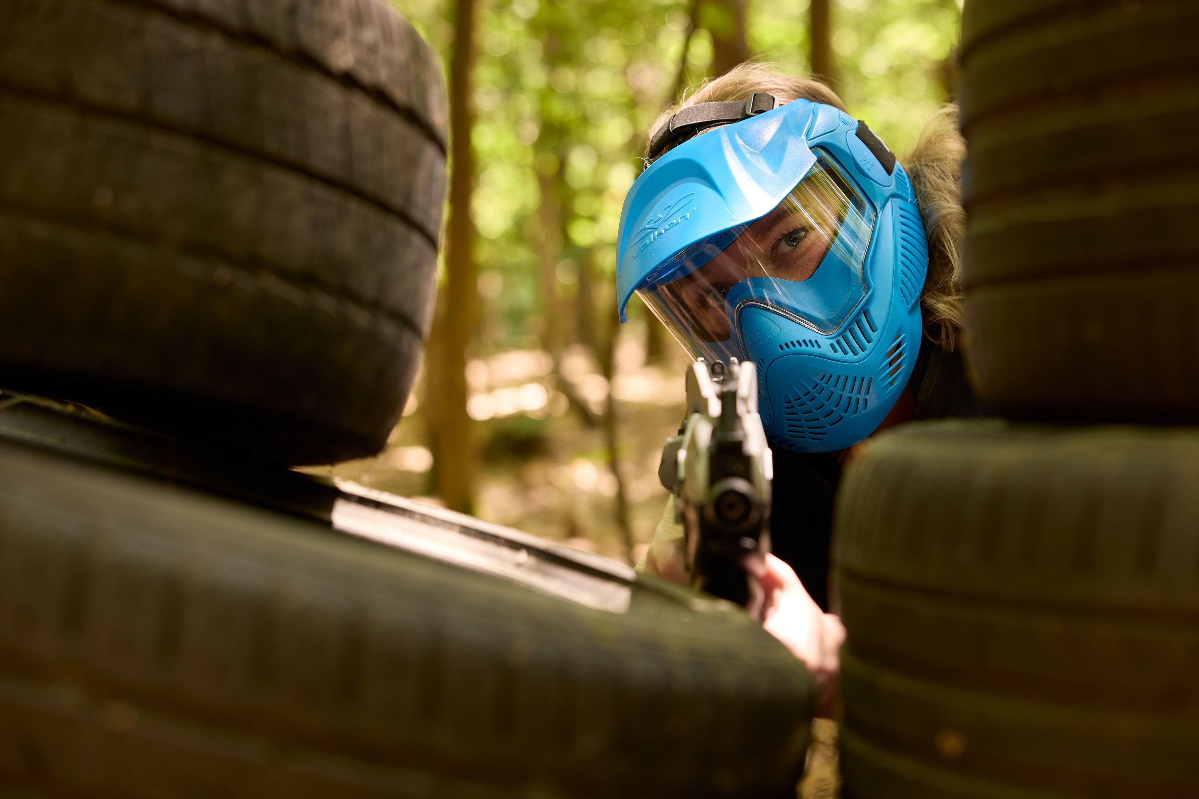 Vrouw tussen stapel banden aan het airsoften bij Klimrijk Brabant
