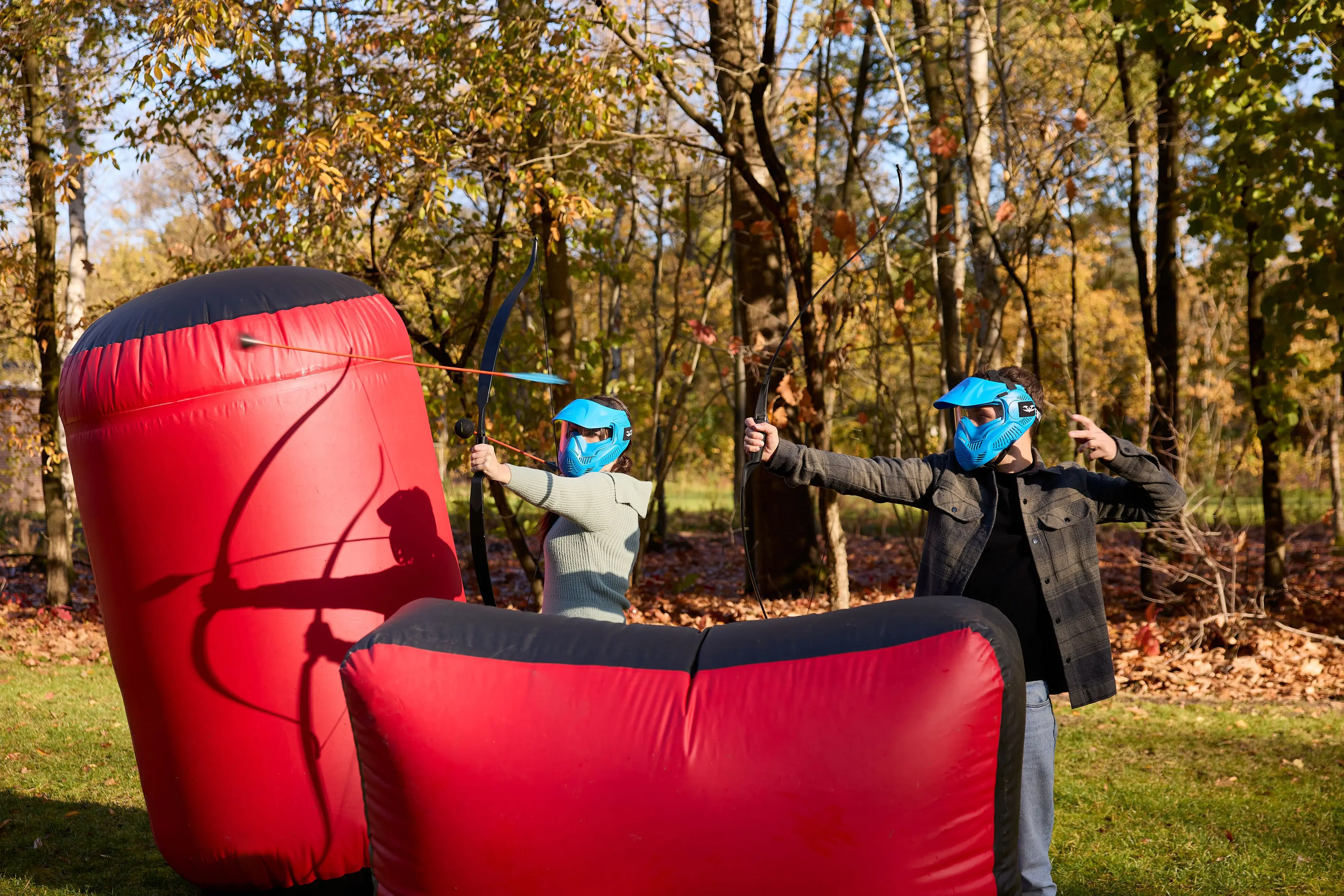Man en vrouw spelen outdoor archery tag met obstakels bij Klimrijk Brabant