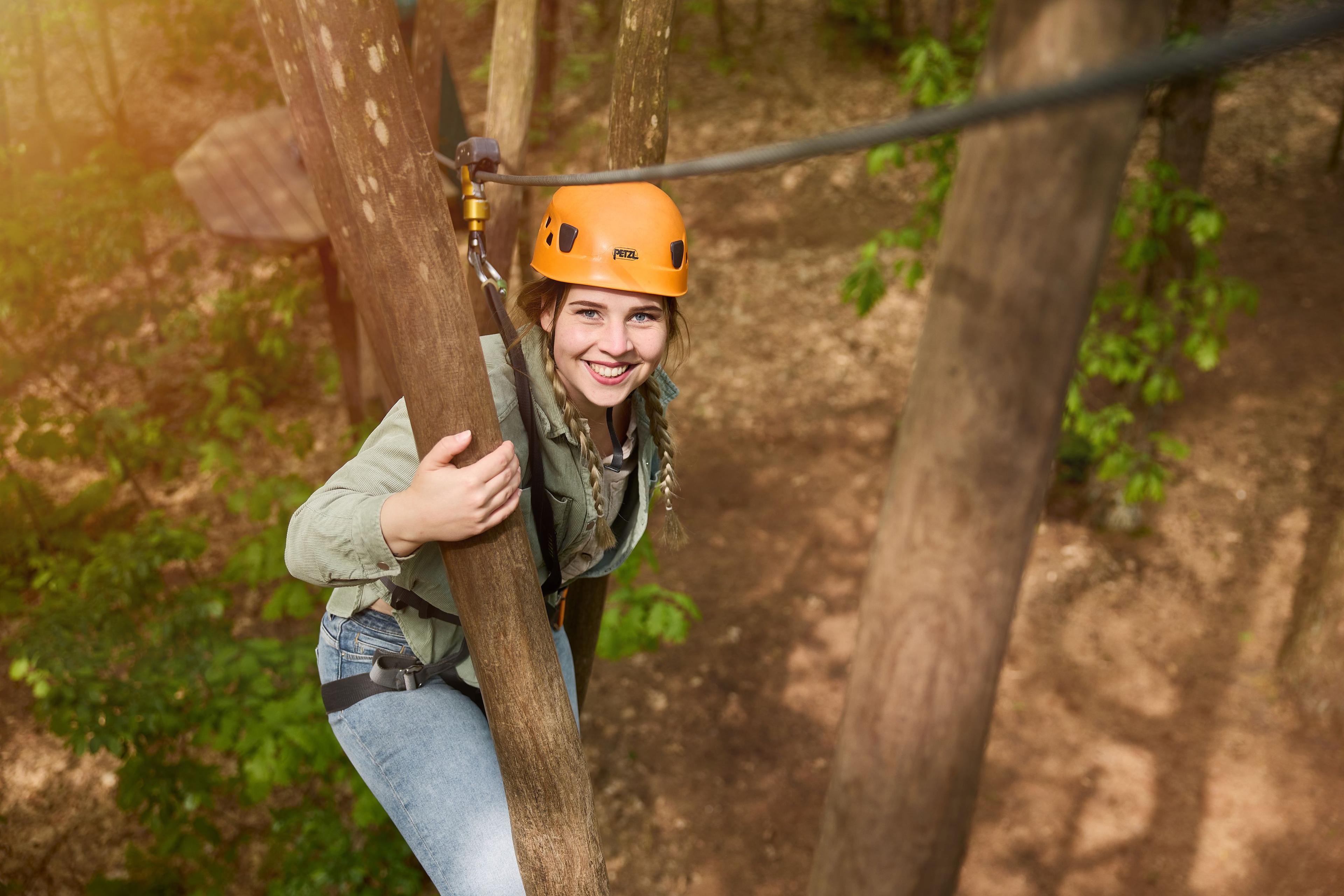 Vrouw op het klimparcours bij boomstam bij Klimrijk Brabant