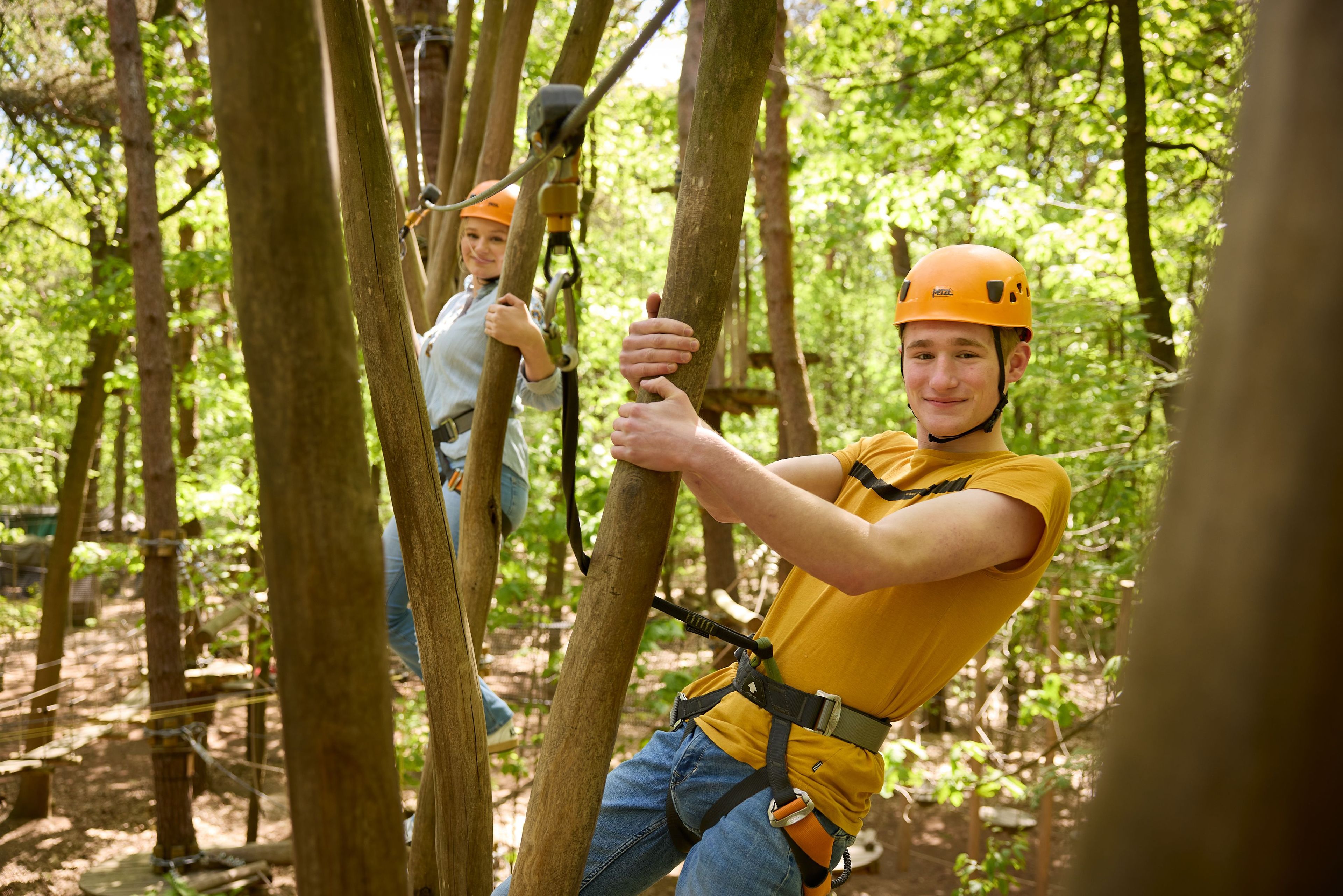 Jongen en meisje op hindernis met palen op het klimparcours bij Klimrijk Brabant