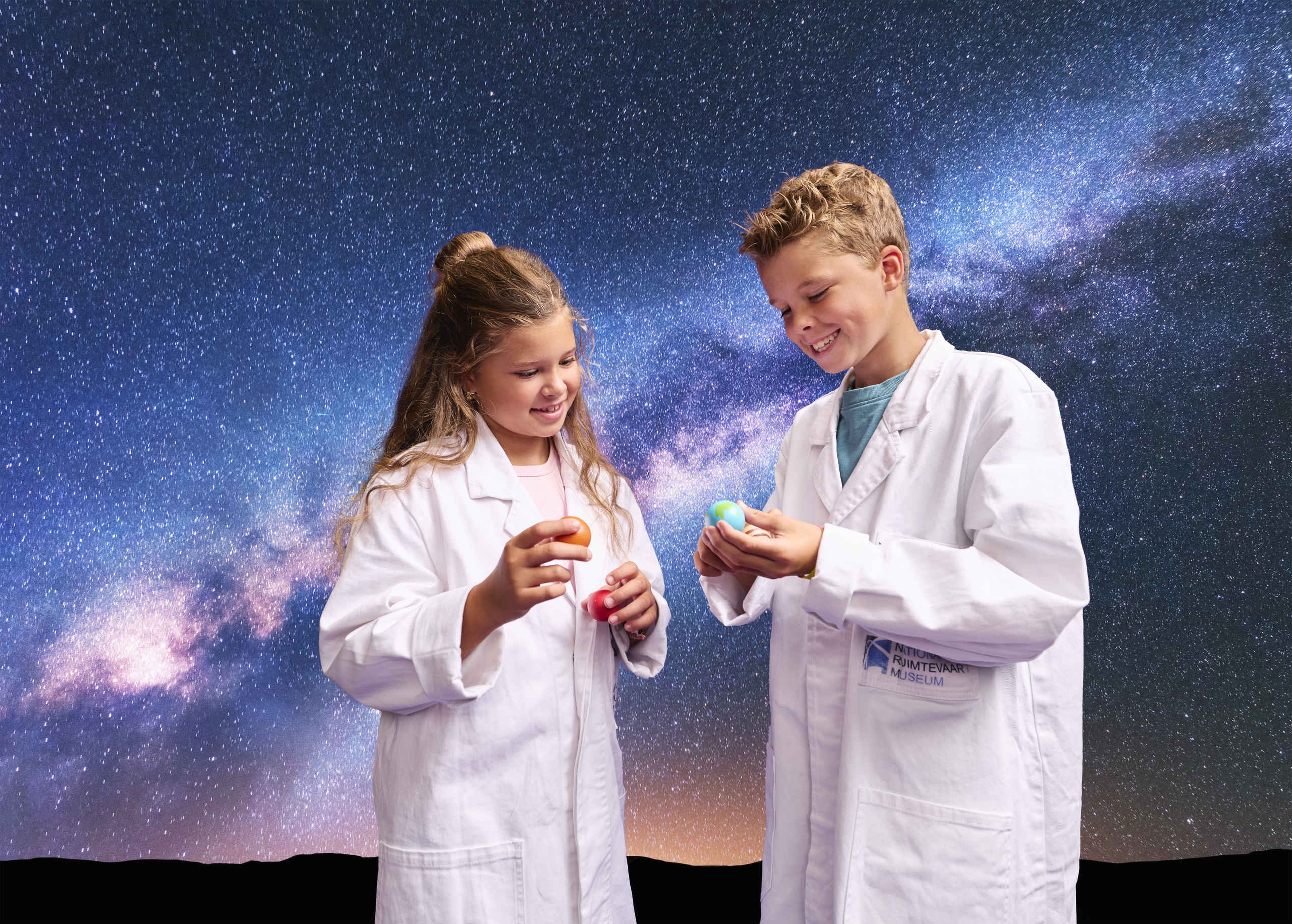 Twee kinderen kijken naar planeten tijdens Space College bij Luchtvaartmuseum Aviodrome.
