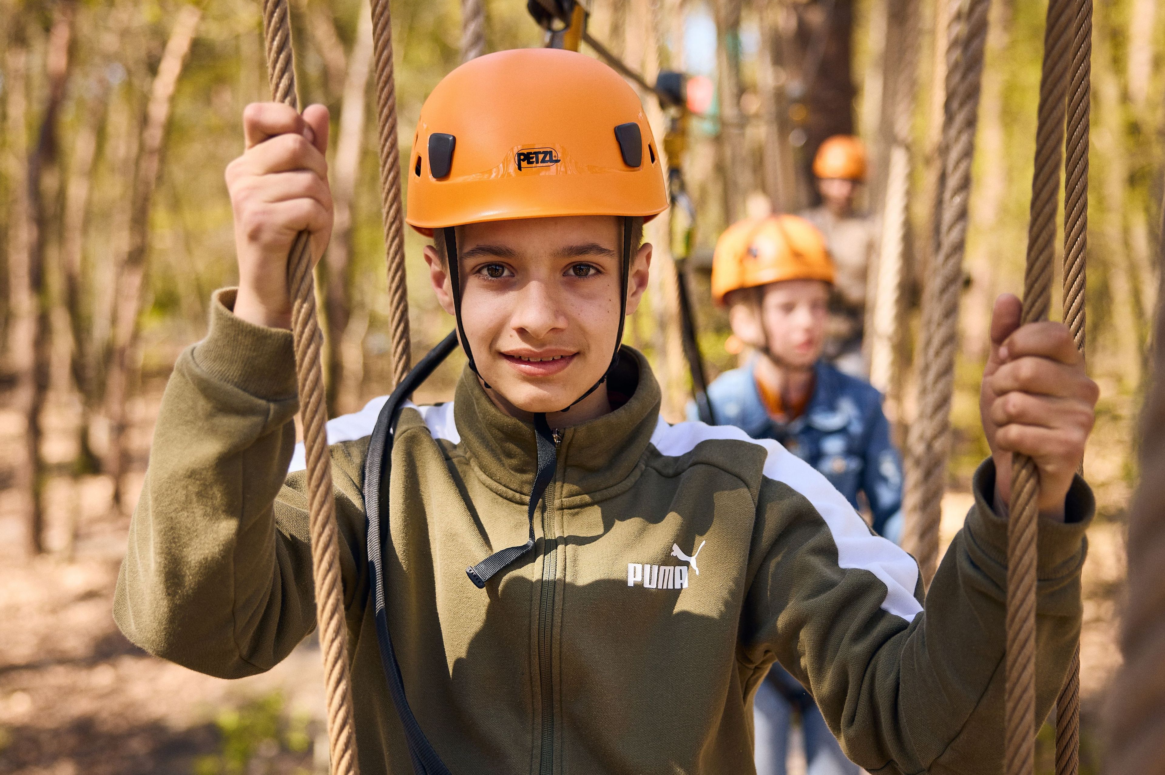 Jongen aan het klimmen tussen touwen op klimparcours bij Klimrijk Brabant