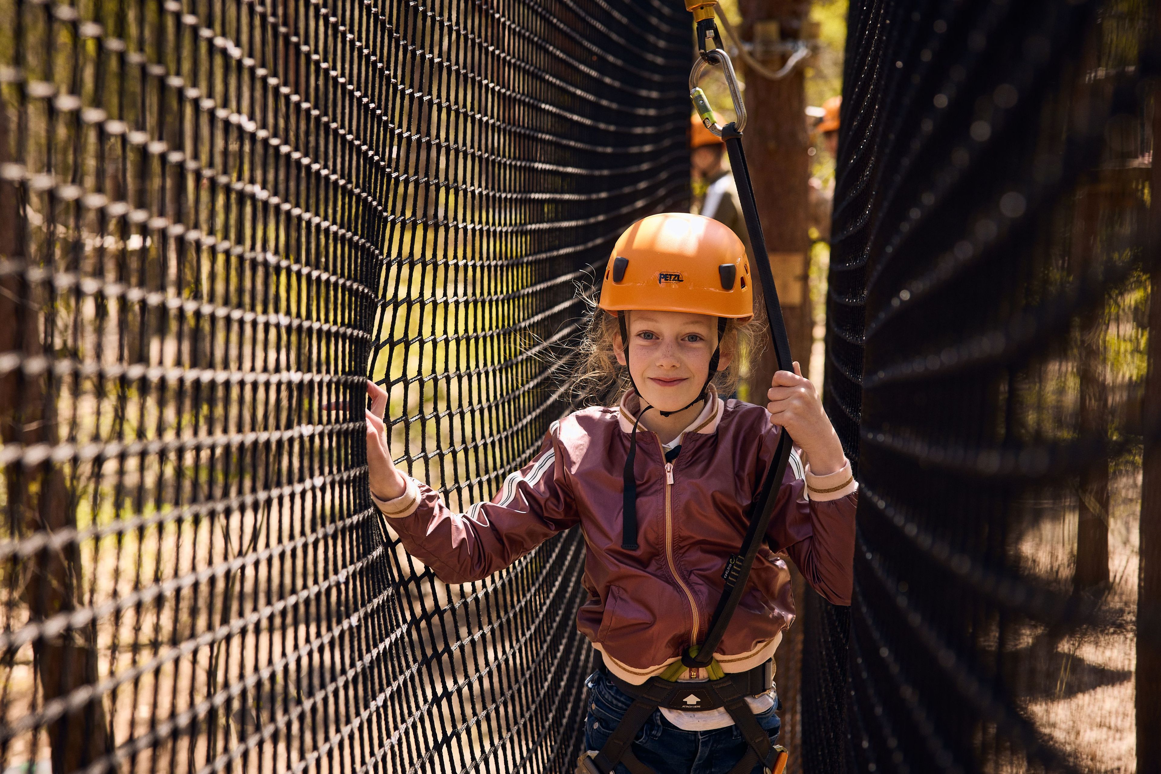 Meisje tussen netten op het klimparcours bij Klimrijk Brabant