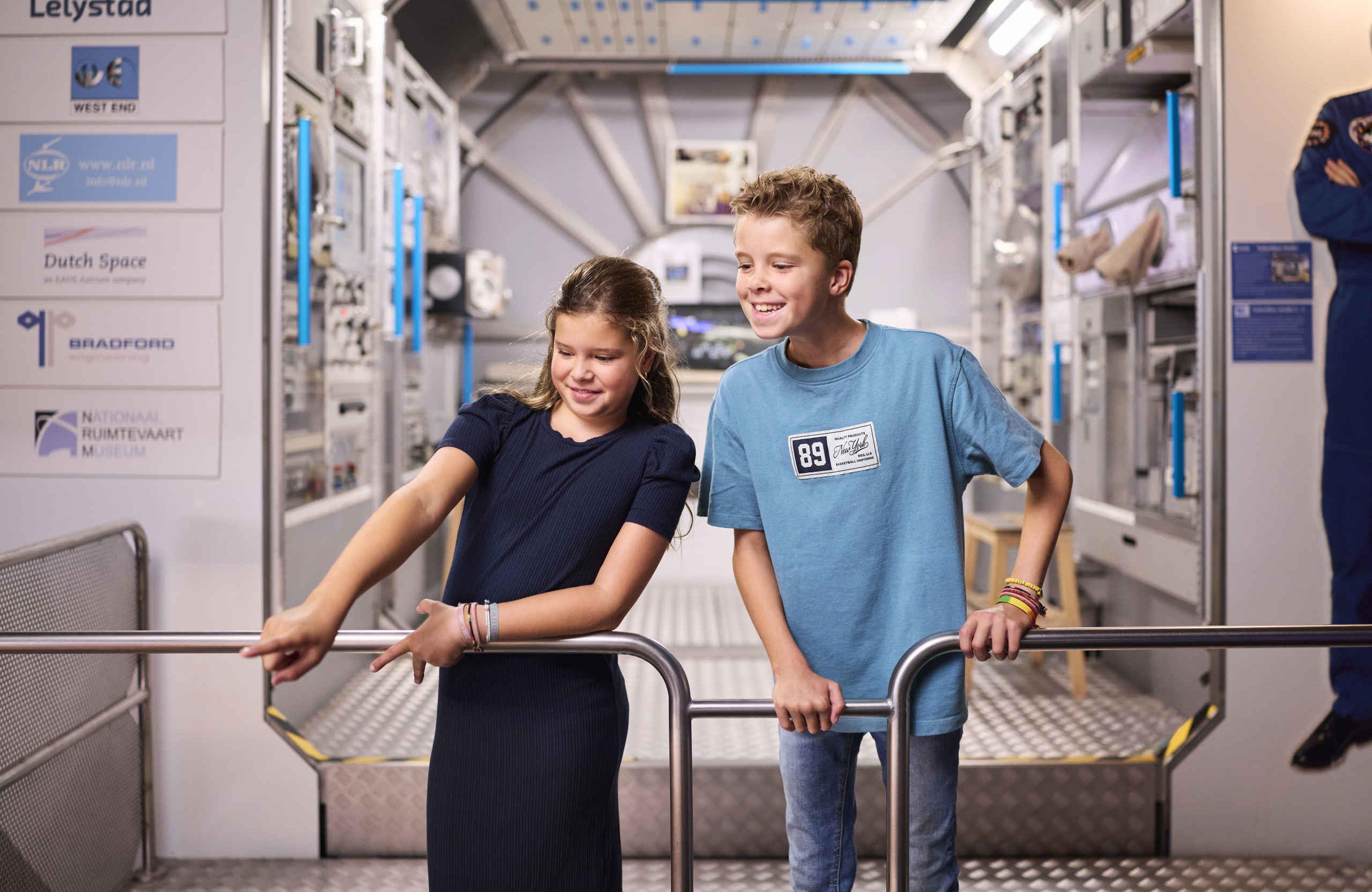 Twee kinderen kijken naar vliegtuigen bij Space College bij Luchtvaartmuseum Aviodrome.