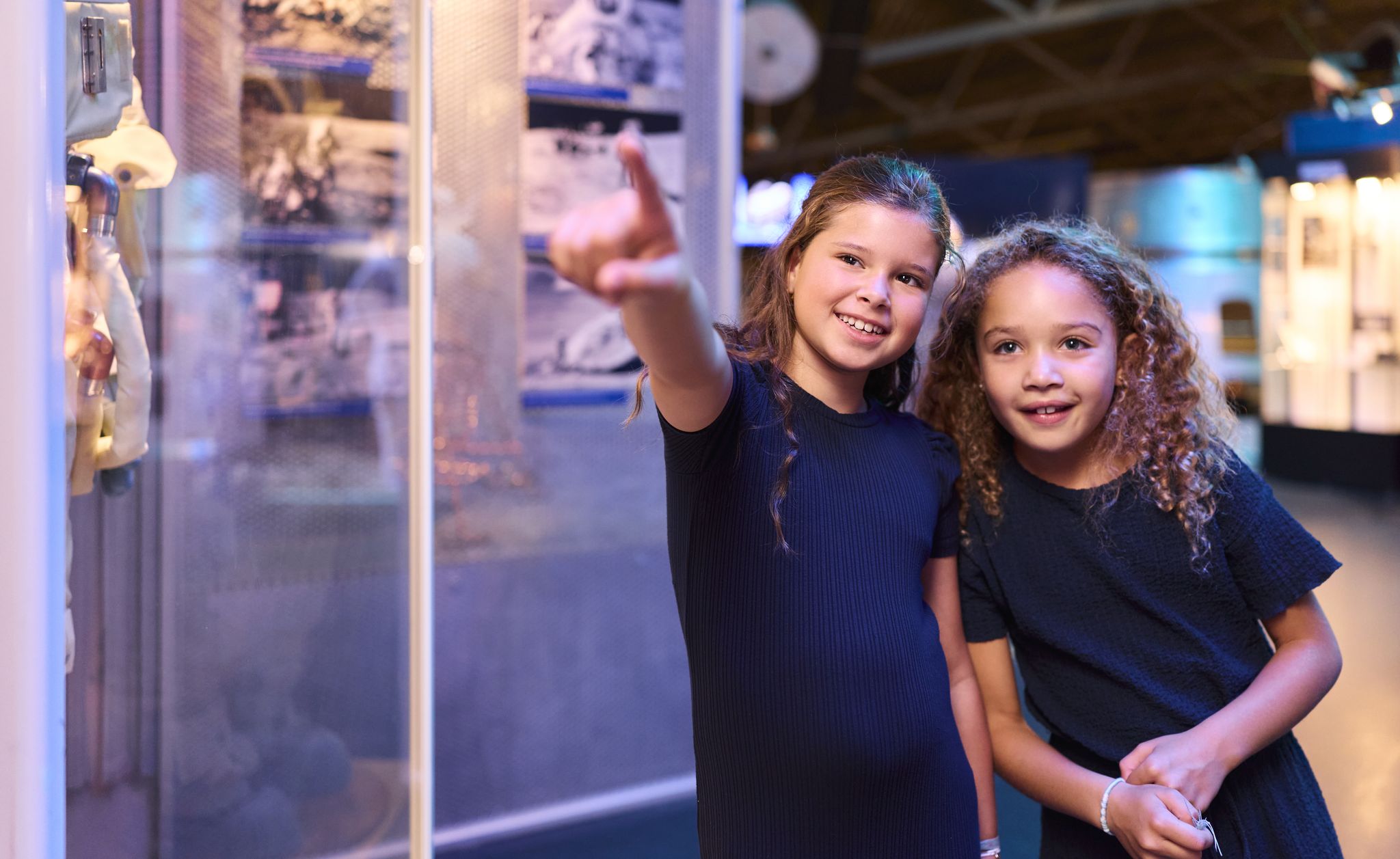 Twee meiden kijken naar een astronaut tijdens Space College bij Luchtvaartmuseum Aviodrome.