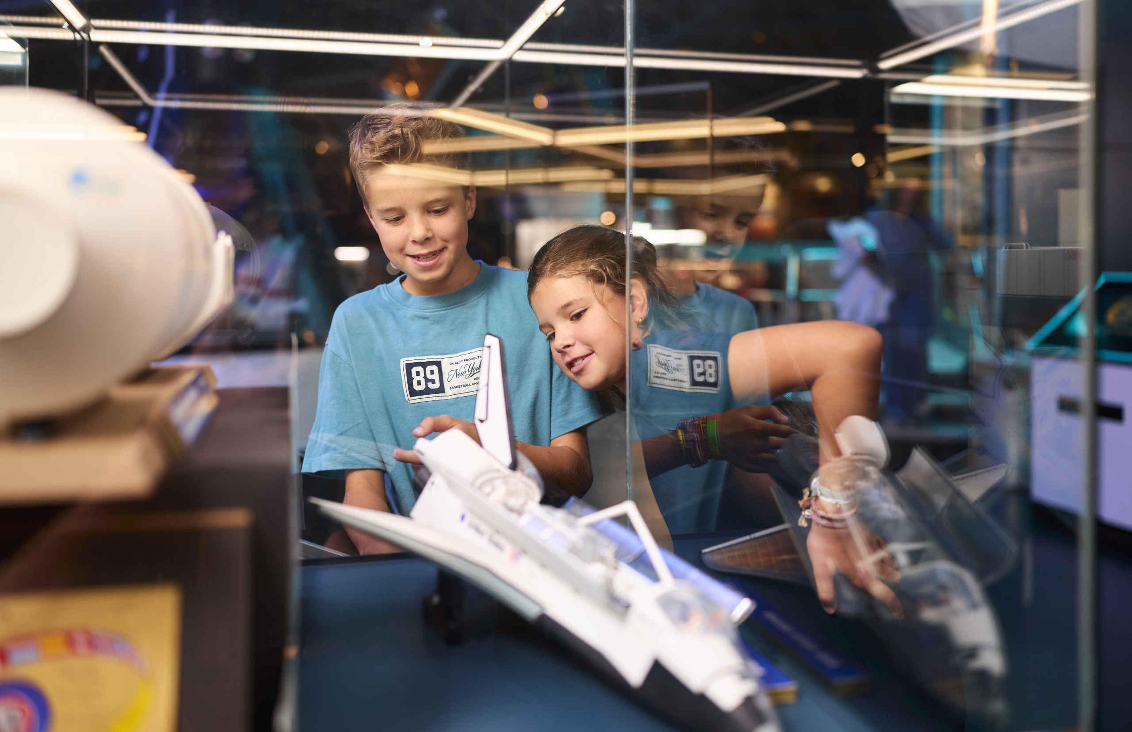 Twee kinderen kijken naar een vliegtuig tijdens Space College bij Luchtvaartmuseum Aviodrome.