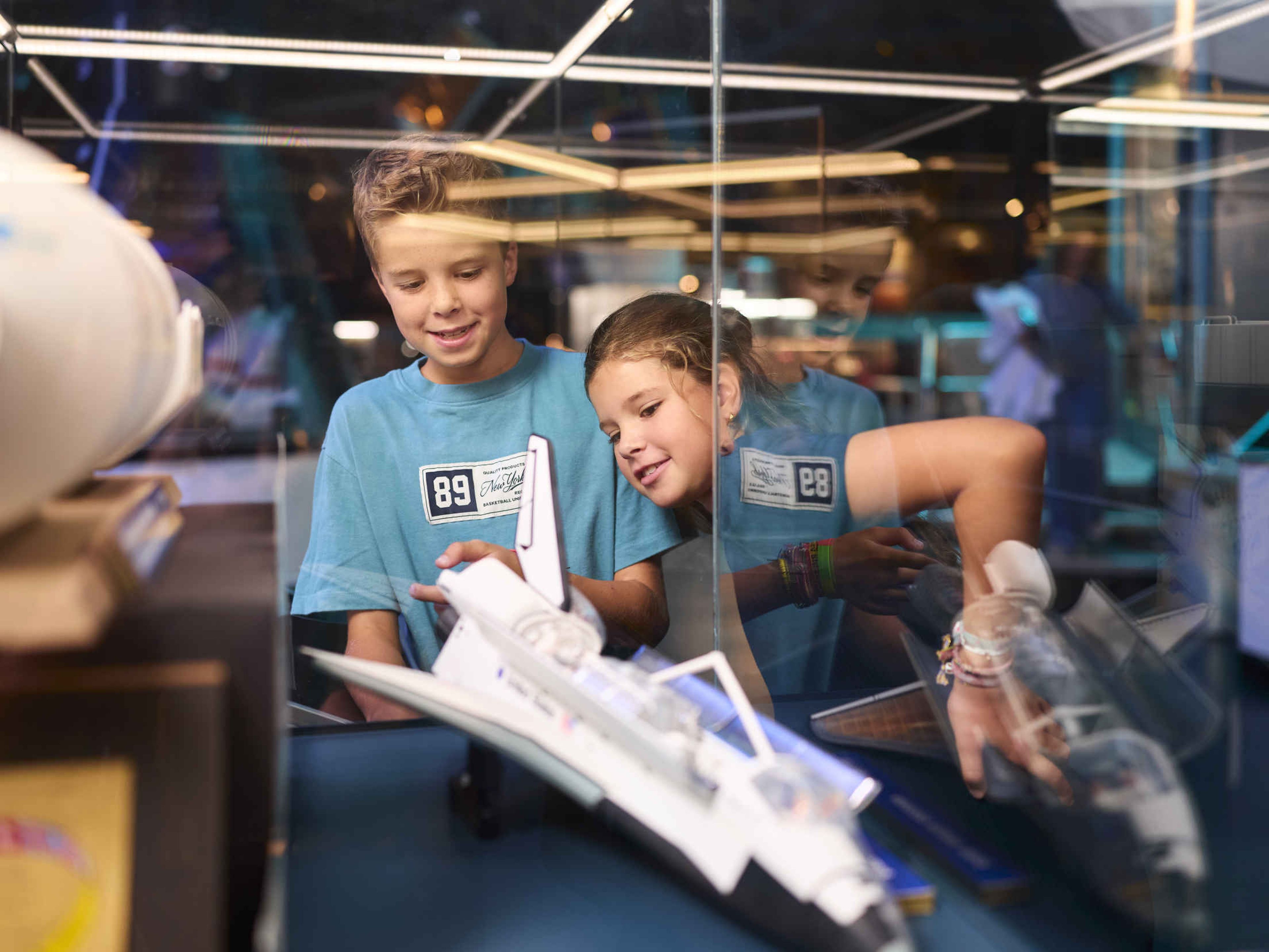 Twee kinderen kijken naar een vliegtuig tijdens Space College bij Luchtvaartmuseum Aviodrome.